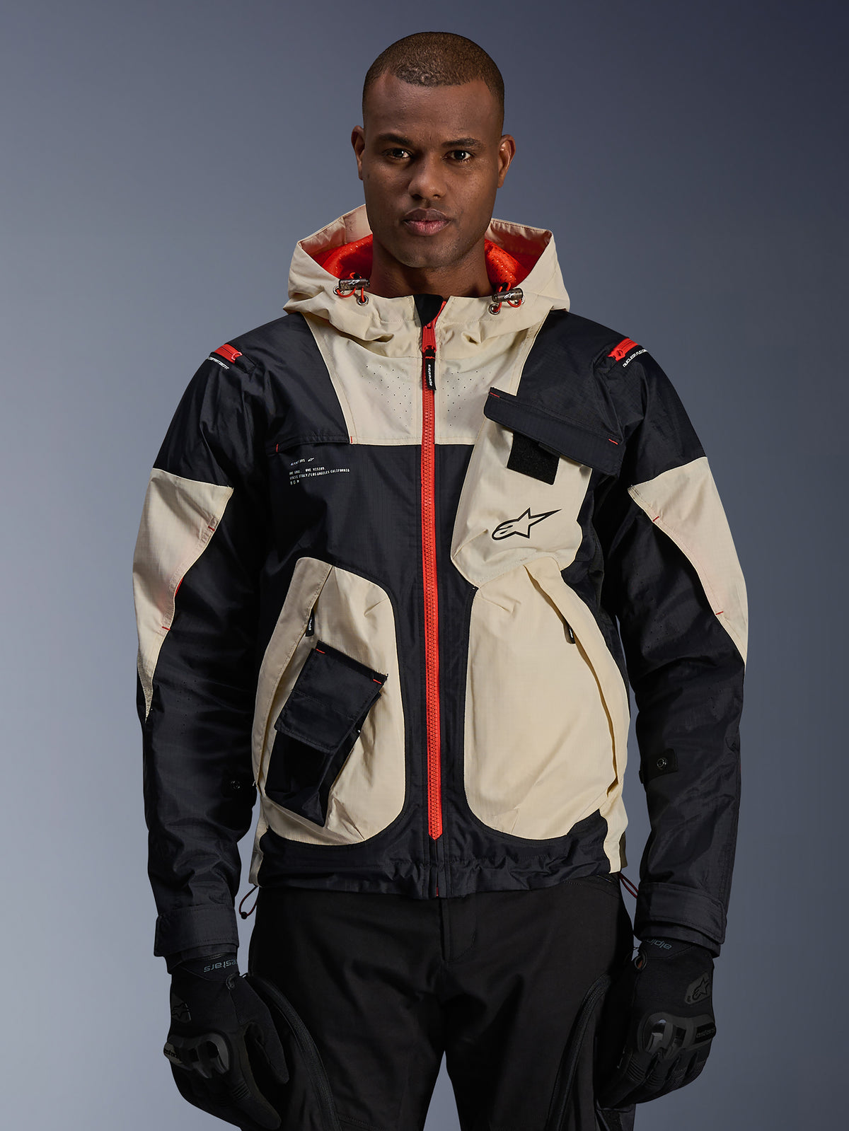 Casaco Alpinestars Mogress Air para homem, modelo urbano em amêndoa, preto e laranja, com capuz e bolsos utilitários.