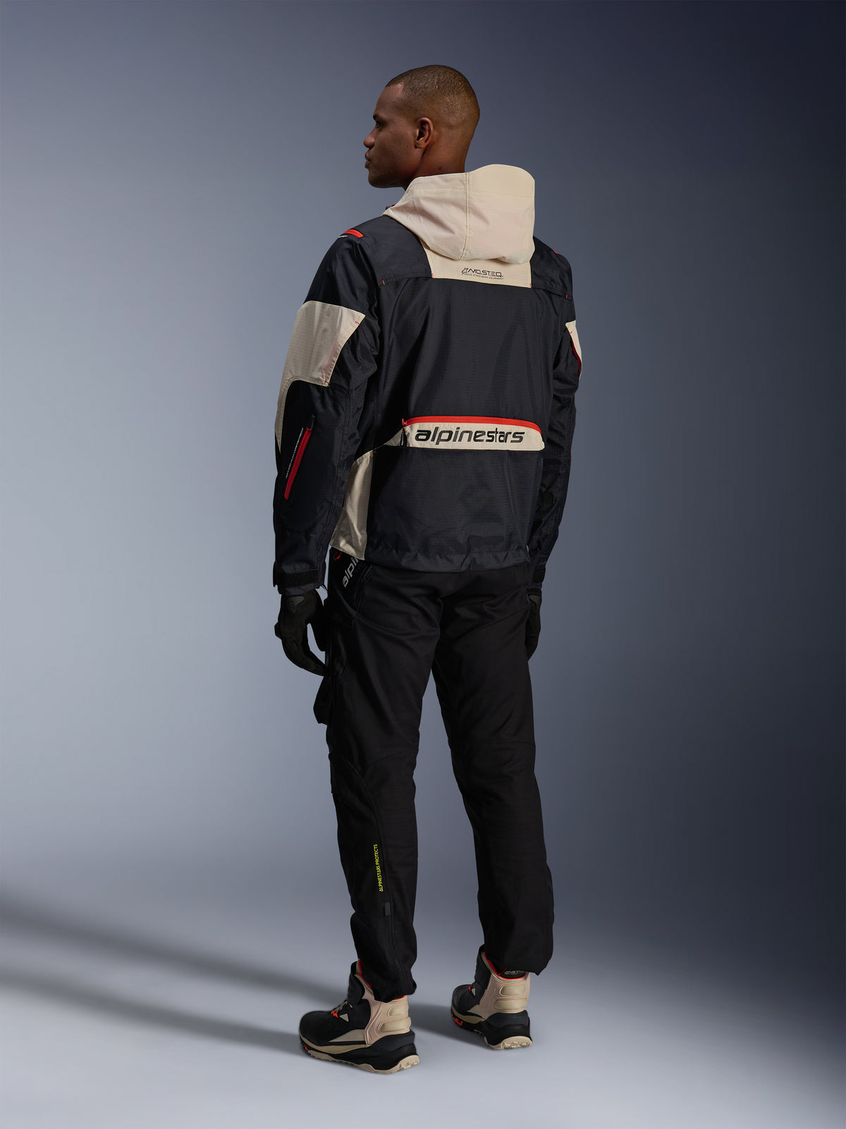 Alpinestars Mogress Air, casaco de moto urbano preto e amêndoa com pormenores laranja, vista traseira.