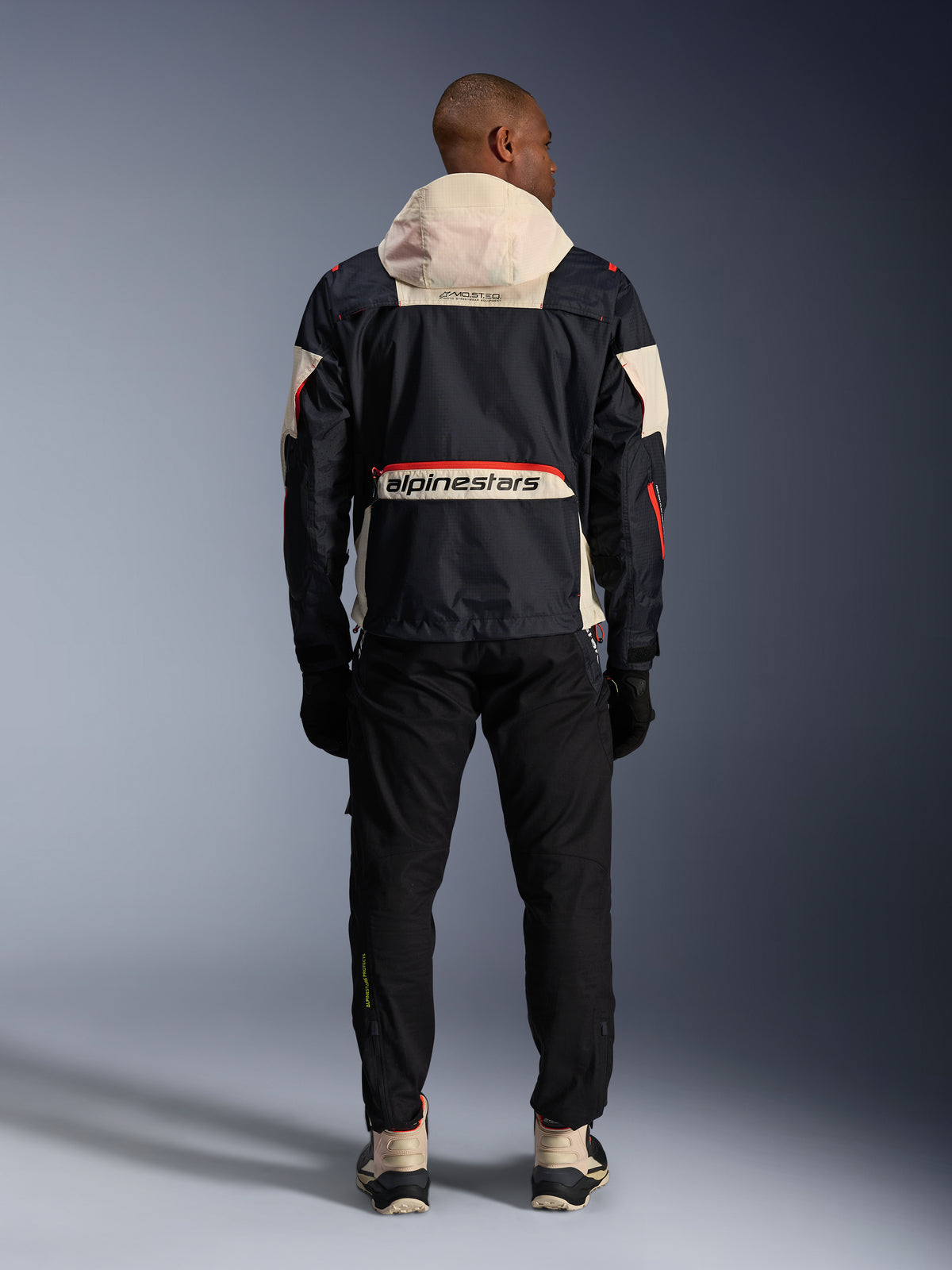 Alpinestars Mogress Air, casaco de moto urbano para homem, preto e laranja com capuz creme, vista traseira.