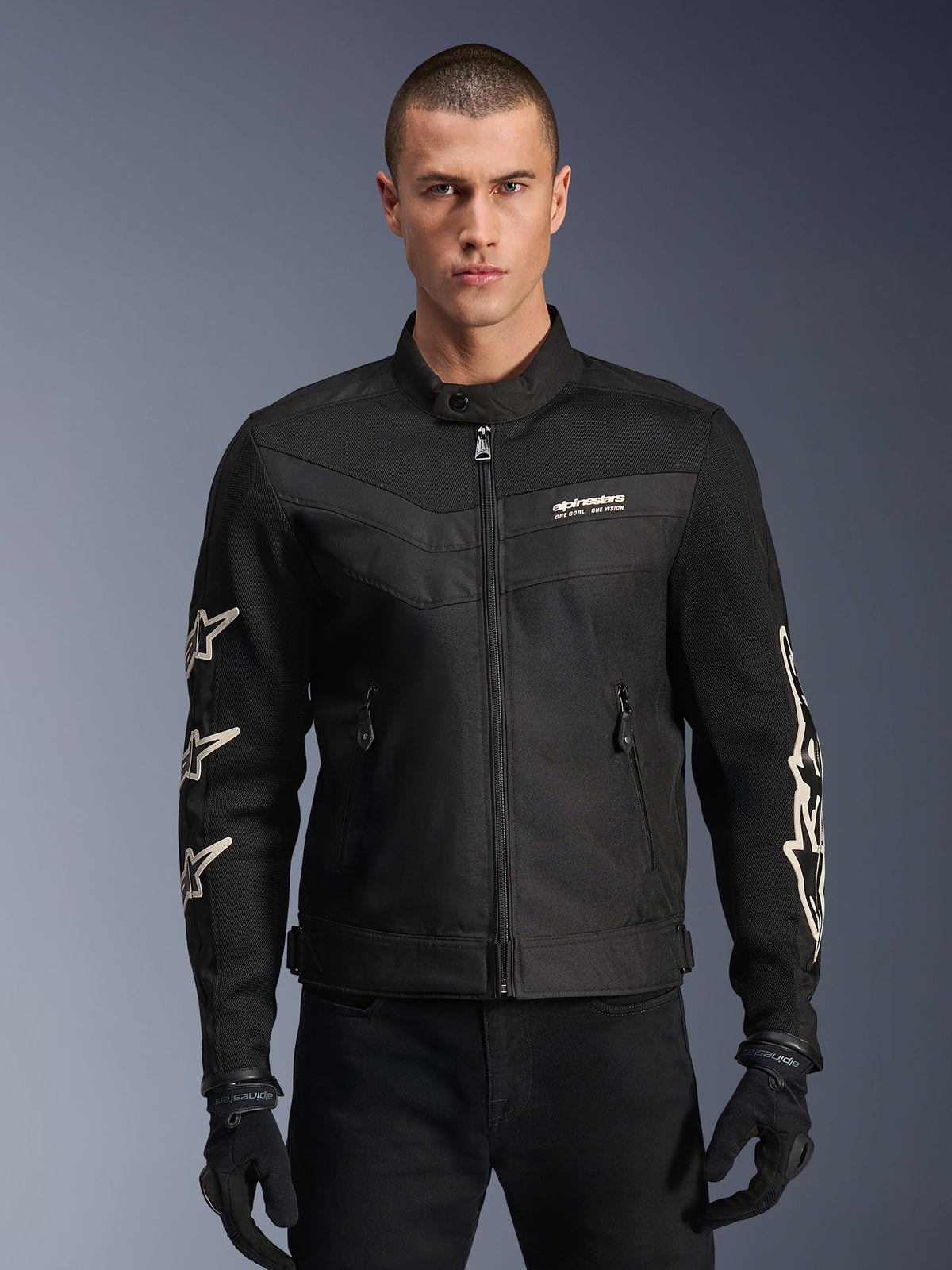 Alpinestars T-Dyno Air Jacket, casaco de motociclismo em têxtil preto, com grafismos de estrelas brancas nas mangas e logótipo no peito, painéis de malha para ventilação, corte de motociclista de inspiração vintage, usado com luvas e calças pretas