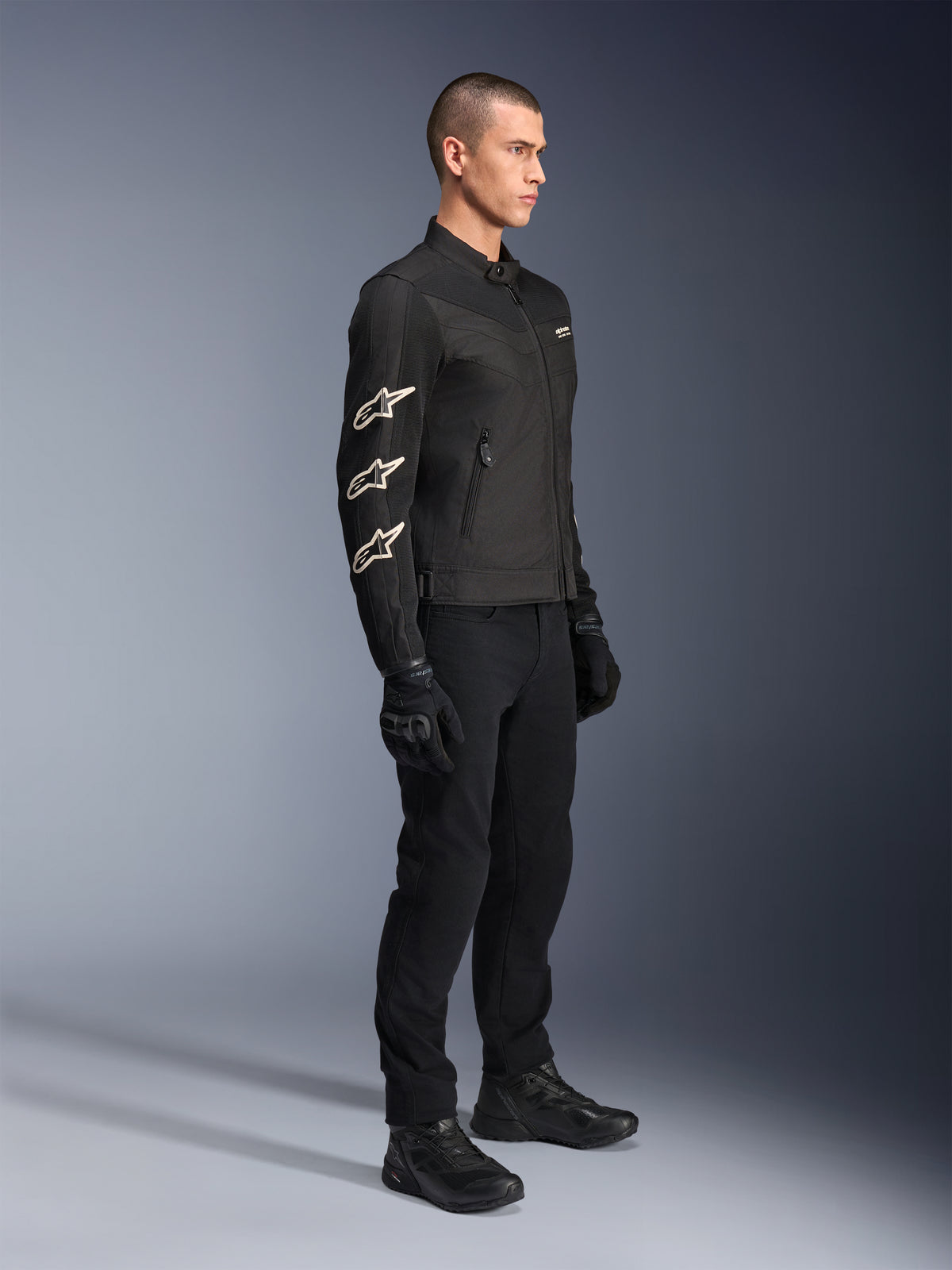 Casaco Alpinestars T-Dyno Air, preto, casaco de motociclismo têxtil, com três logótipos Alpinestars brancos na manga, usado com calças e luvas pretas a condizer, equipamento de condução urbana com painéis de malha respirável
