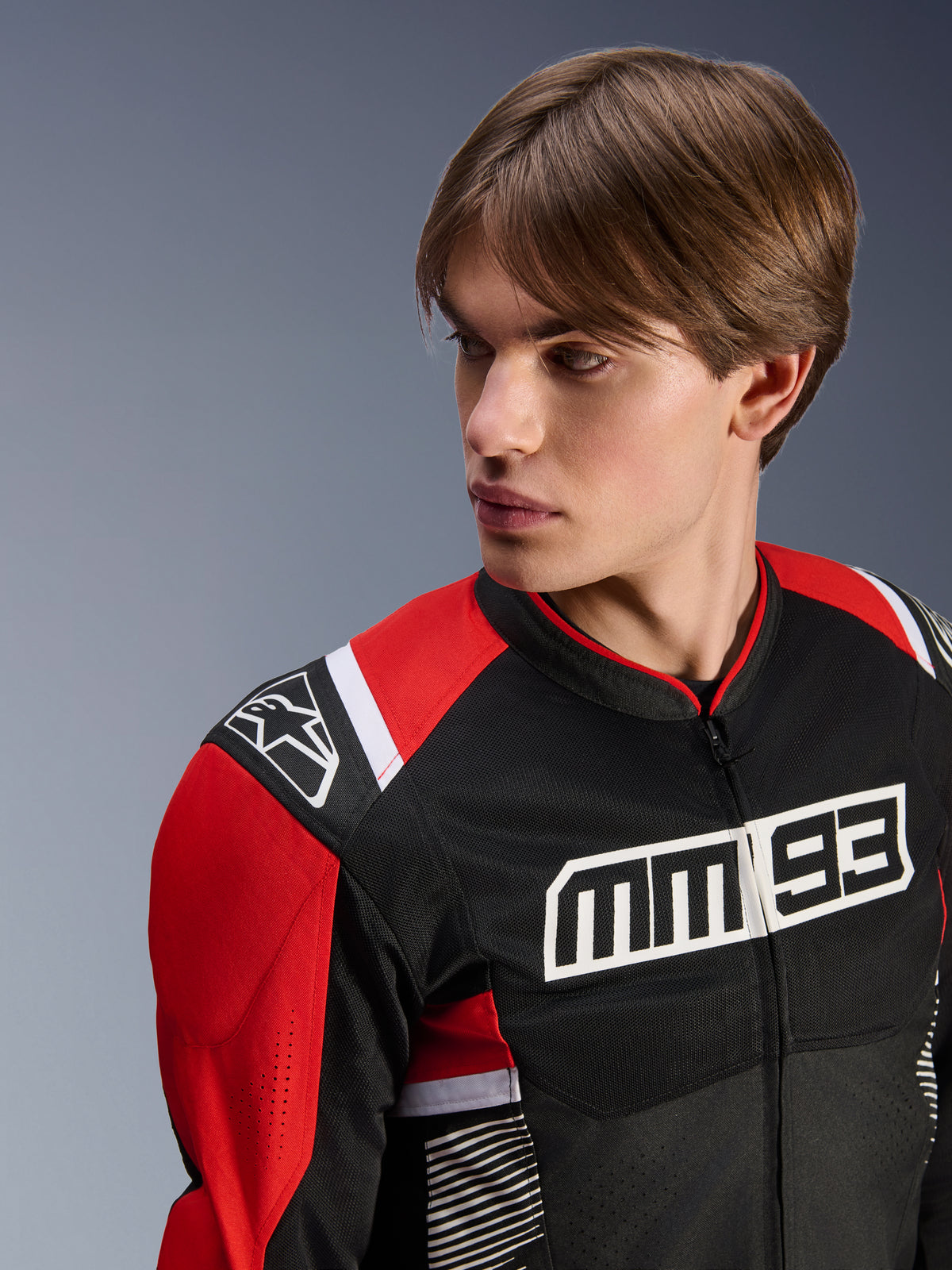 Male model wearing Alpinestars MM93 T-SPS Air V2 Jacket, Textile Motorcycle Jacket, Black Bright Red and White, featuring bold MM 93 branding on the chest and star logo on the shoulder, mesh construction for airflow, sport-oriented riding gear