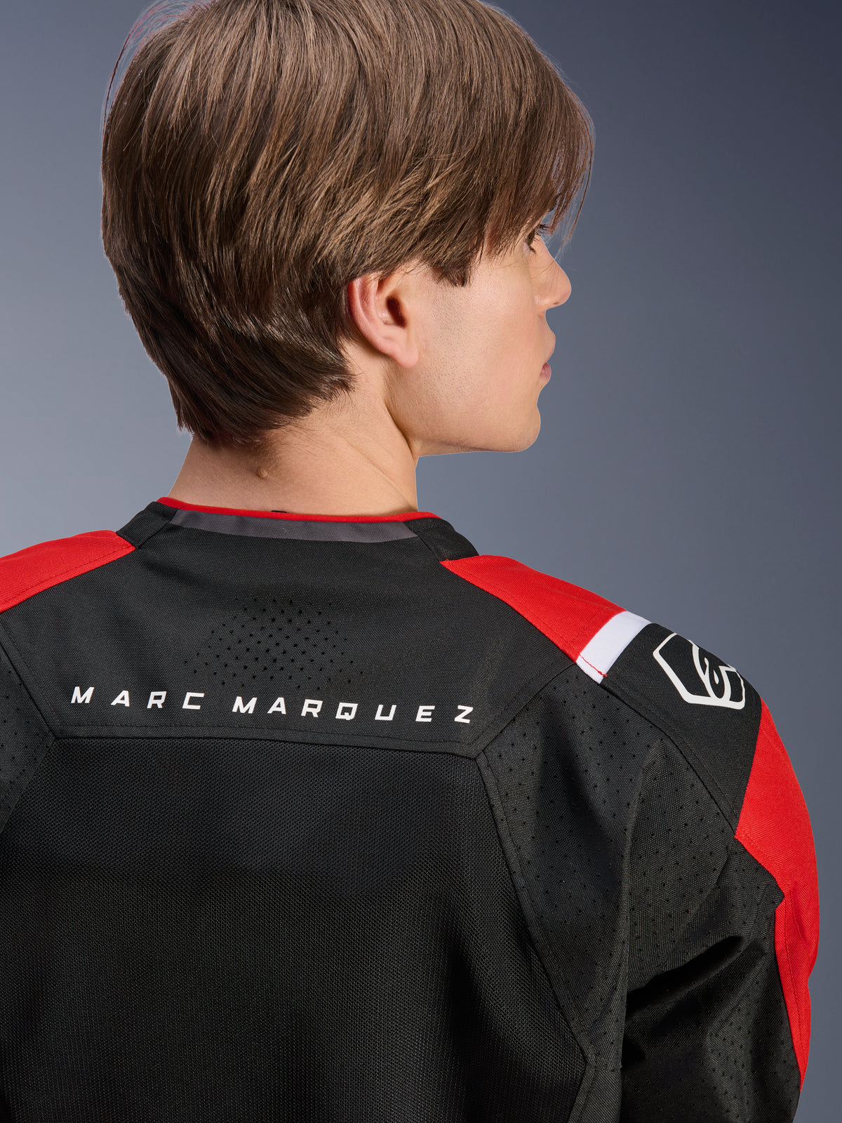 Alpinestars MM93 T-SPS Air V2 Jacket, rear view of the upper back and shoulders, Black with Bright Red and White details, 'MARC MARQUEZ' text across the yoke, featuring technical mesh panels and shoulder logo, urban sport motorcycle apparel