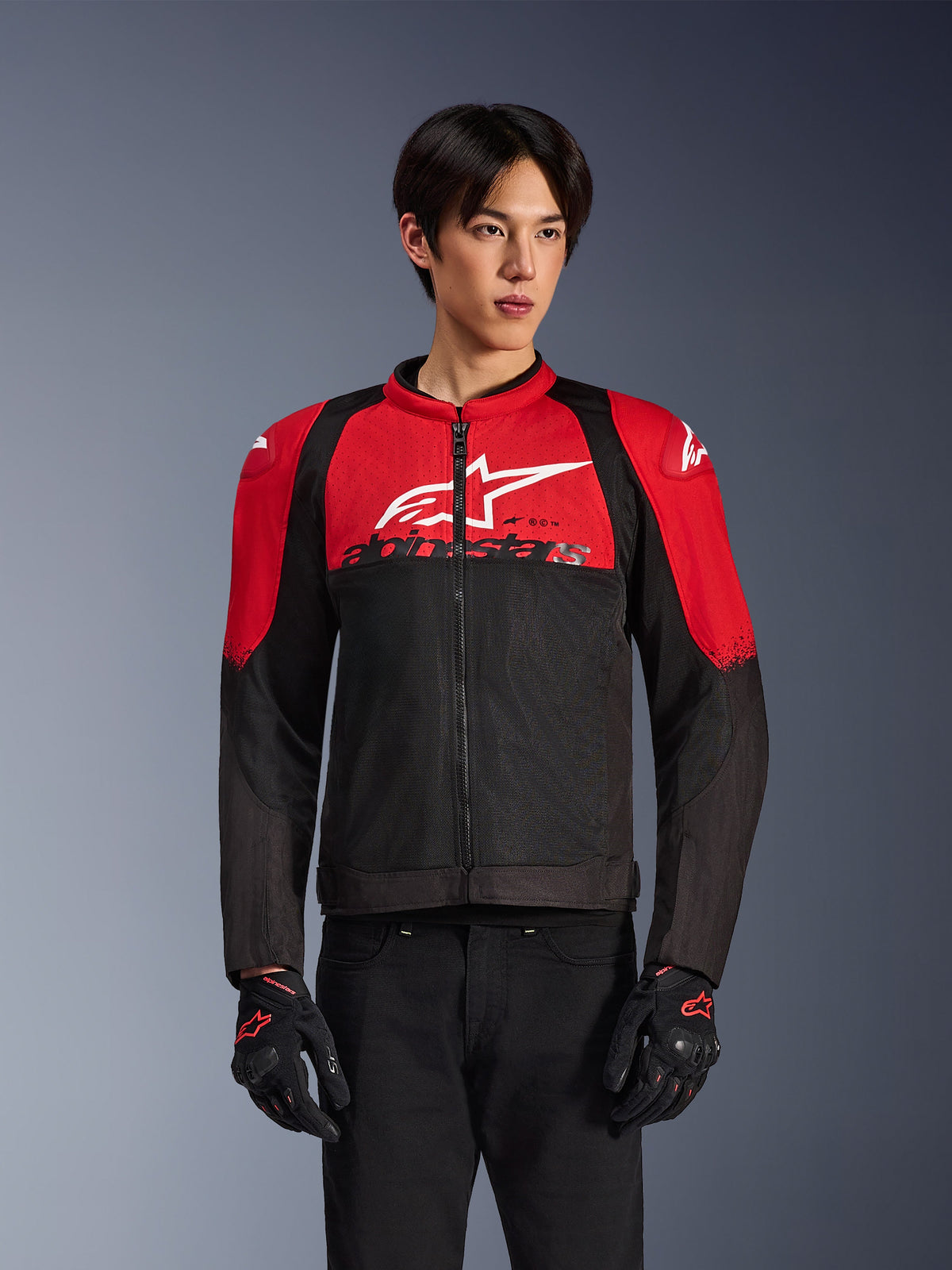 Alpinestars SMX Air Jacket, casaco de malha para motociclismo, vermelho vivo e preto, usado por um modelo com luvas de motociclismo pretas, com um grande logótipo branco no peito, construção em têxtil ventilado com painéis vermelhos nos ombros e mangas pretas, equipamento de performance desportivo para condução em tempo quente