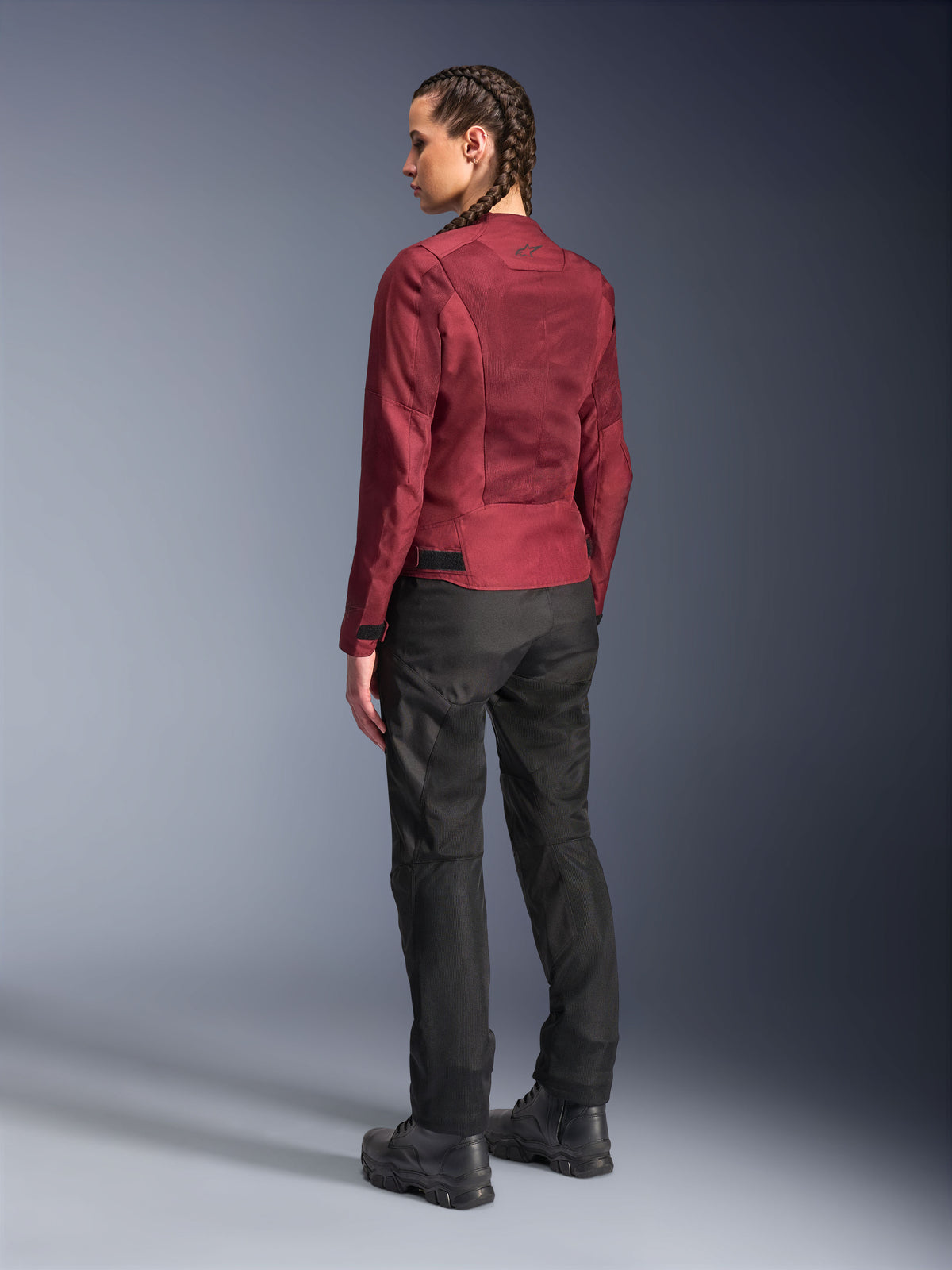 Condutora com Casaco Alpinestars Stella C-1 Air em bordeaux e Calças Stella C-1 Air em preto, vista traseira de corpo inteiro, equipamento de motociclismo urbano com painéis de malha técnica, combinado com botas de condução pretas