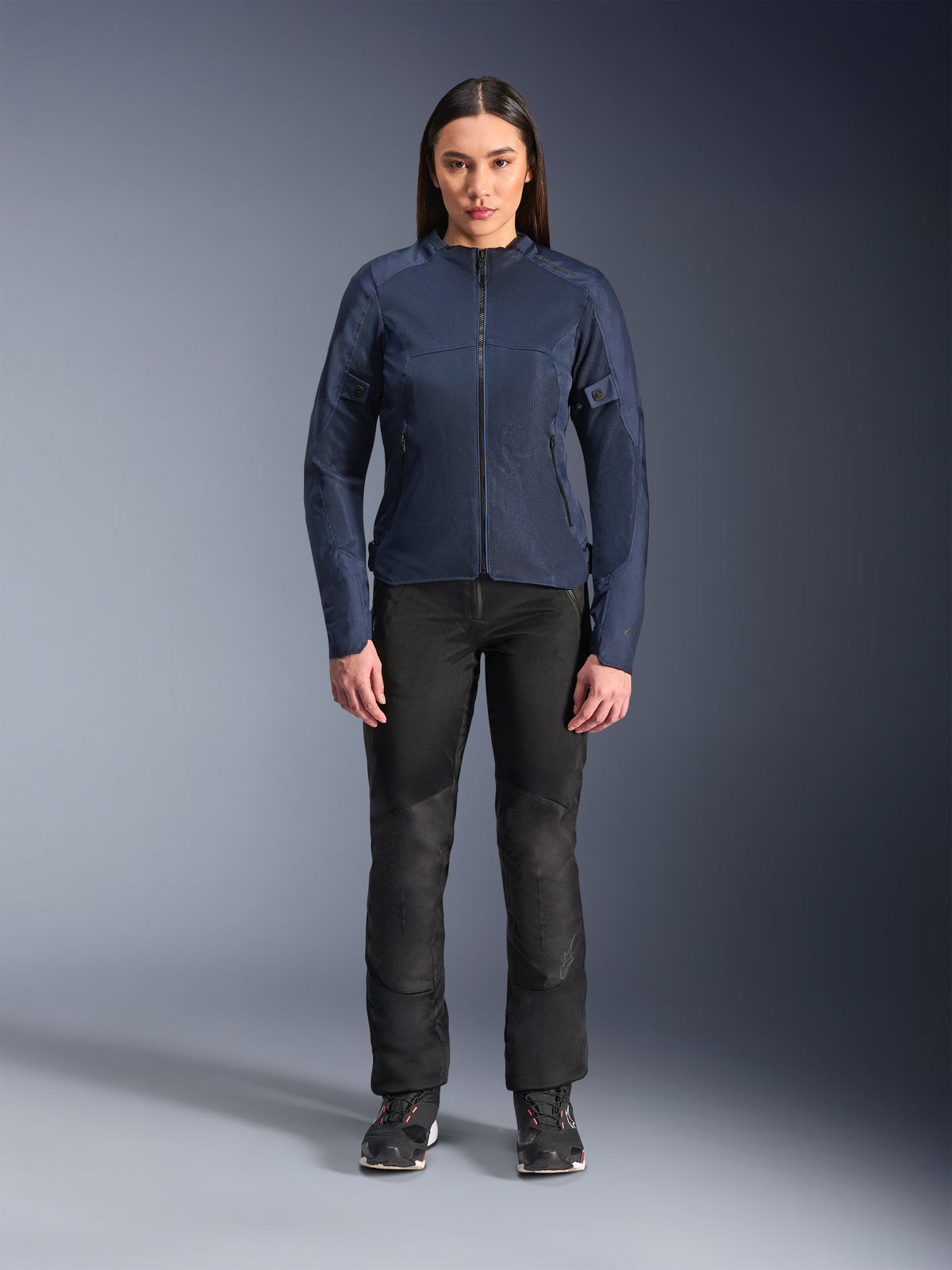 Modelo feminina a usar blusão Alpinestars Stella C-1 Air em Azul, blusão de motociclismo urbano com painéis de malha técnica, combinado com calças de motociclismo pretas e sapatilhas pretas, vista frontal em estúdio