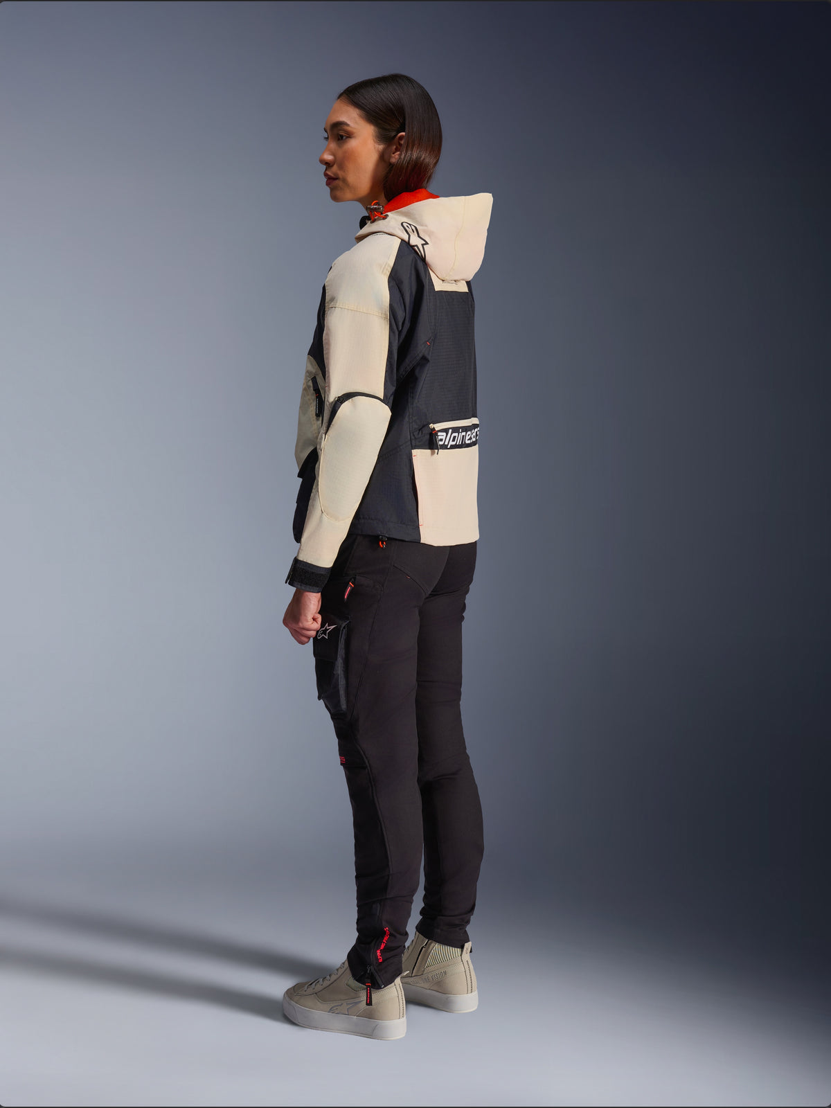 Alpinestars Molly Air Jacket, casaco de motociclismo para mulher, cor Black Almond, com design de capuz, mangas creme e tronco preto, combinado com calças de condução pretas e sapatilhas beges, estilo urbano contemporâneo.