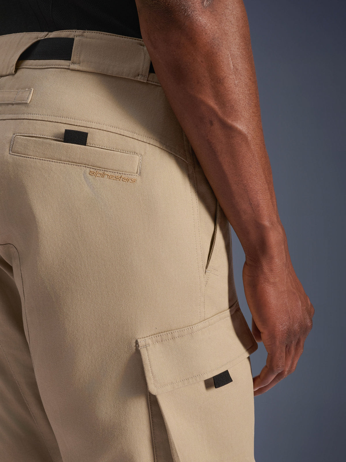 Alpinestars Flex-AST Cargo Pants - Curtas, bege claro, pormenor lateral do bolso cargo com puxador preto e logótipo bordado no bolso traseiro, material têxtil durável, equipamento de motociclismo urbano