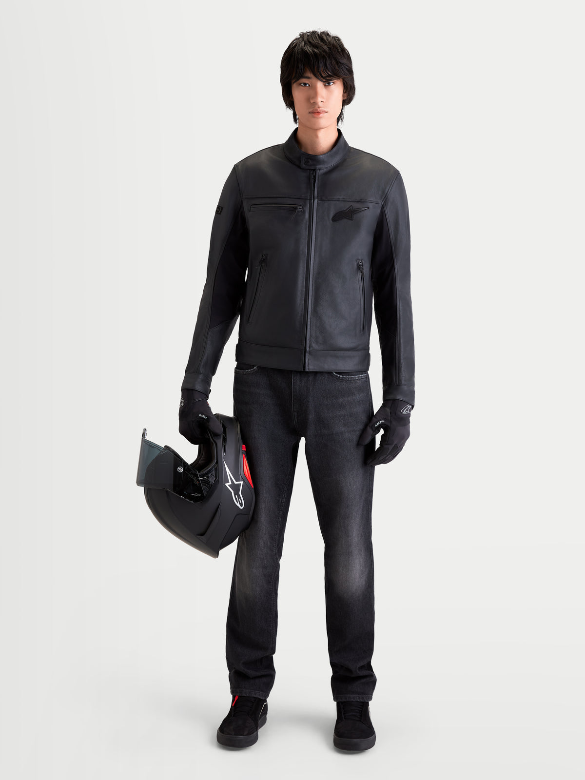Alpinestars Flex Ast 7 Denim Calças Short, calças de ganga de moto urbanas para homem em preto desbotado, vista frontal num modelo a segurar um capacete e um casaco a combinar, com proteção certificada AA e construção elástica