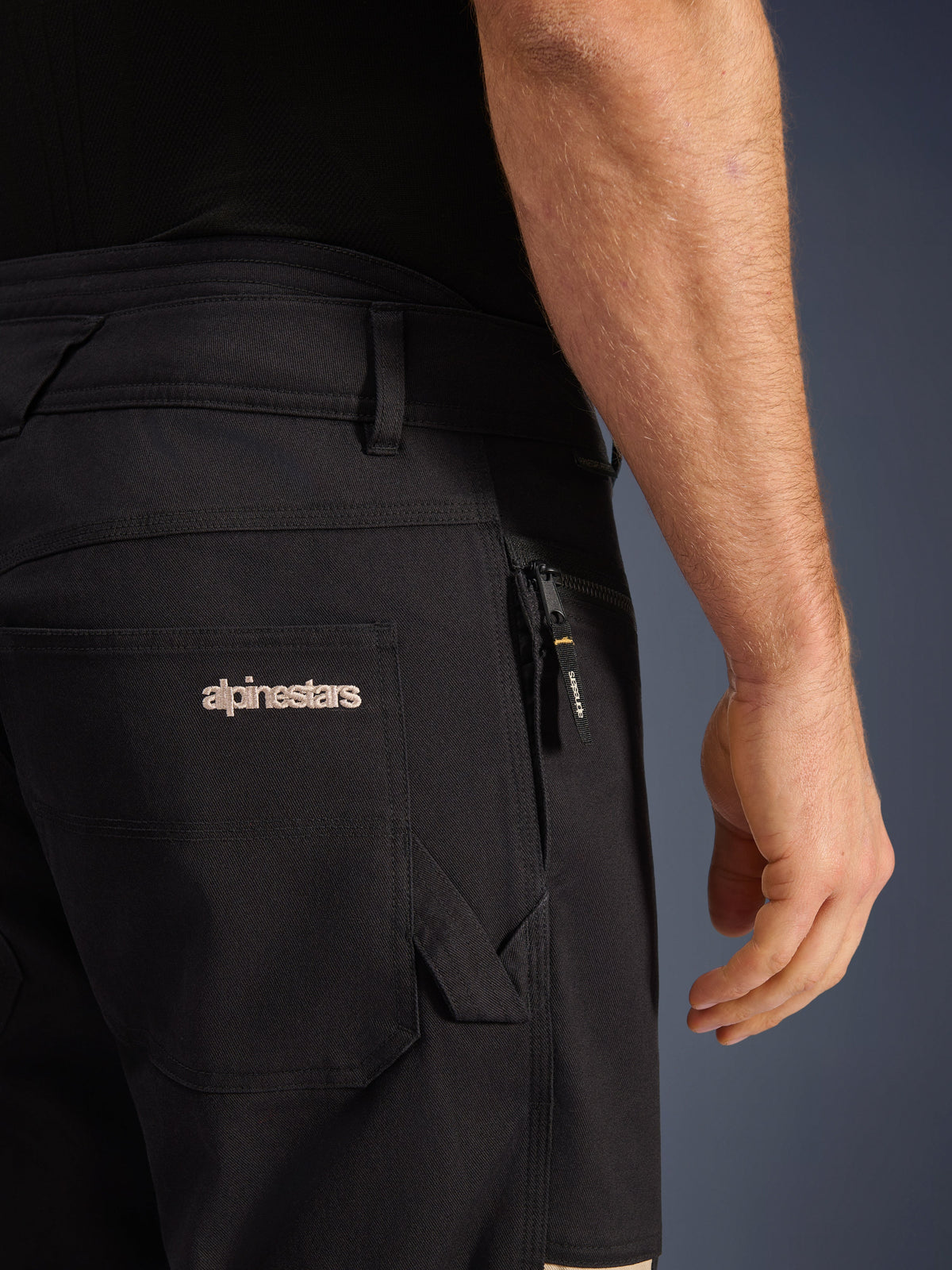 Calças Alpinestars Flex-AST Canvas, calças urbanas de motociclismo, Black Aluminum, pormenor dos bolsos traseiro e lateral com logótipo Alpinestars bordado, bolso com fecho de correr e puxador da marca, construção em sarja elástica durável.