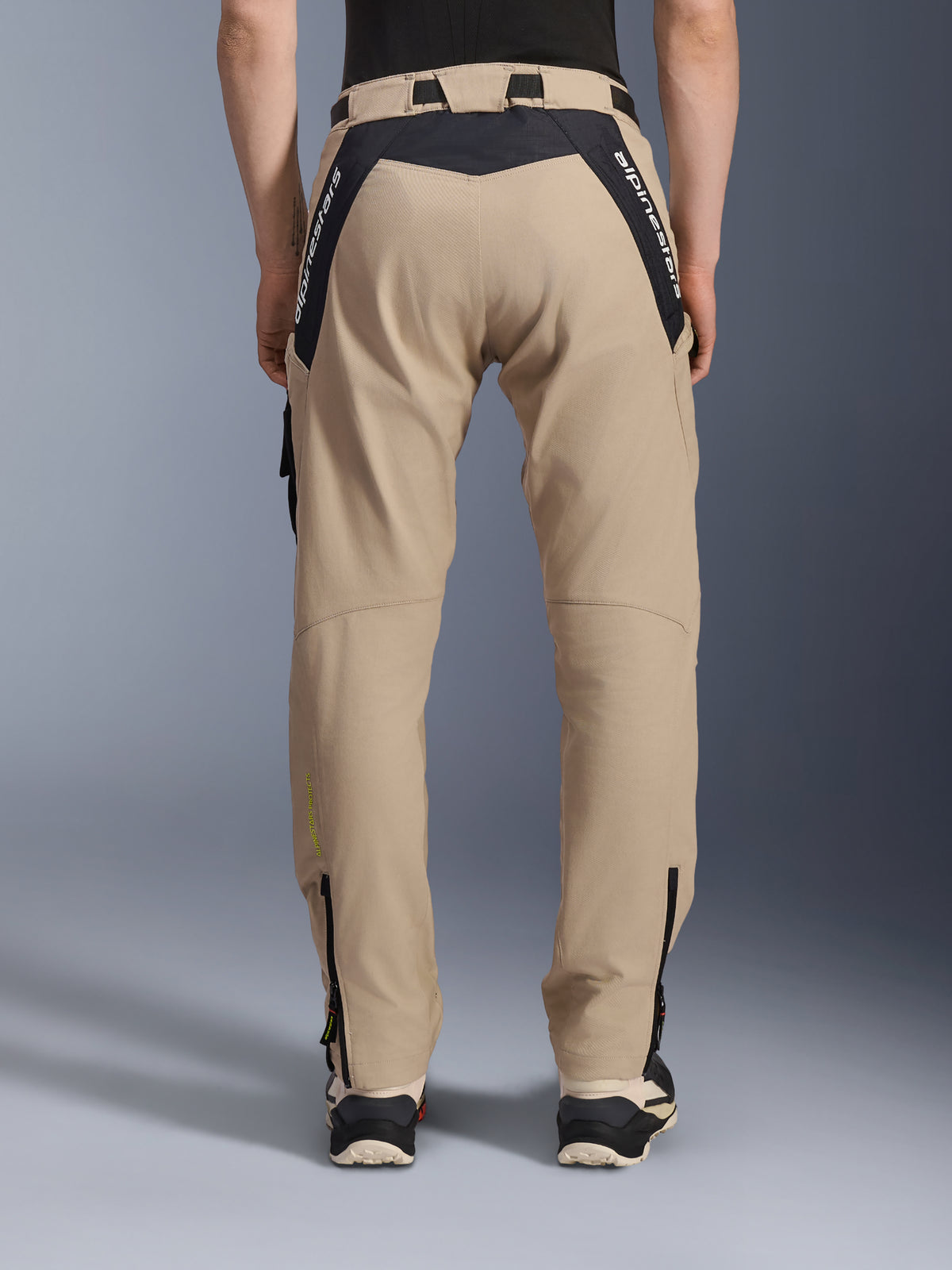 Calças Alpinestars Acteon, calças urbanas de motociclismo, areia, vista traseira com painéis pretos em ripstop e logótipo branco na pala traseira, corte afunilado com fechos de correr na parte inferior das pernas, equipamento contemporâneo para condução em estrada