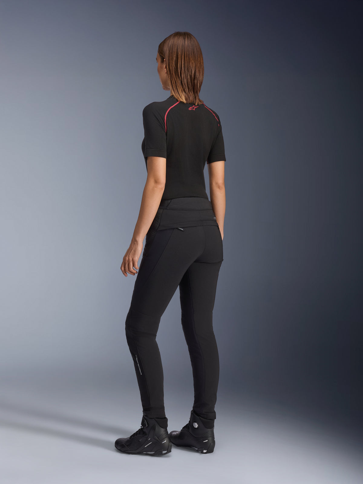 Alpinestars Alamosa Women Pants, Black, Slim-fit Urban Riding Pants shown from the rear, featuring quilted detailing on the back waist, minimalist design with a technical softshell construction, styled with riding shoes and a black base layer