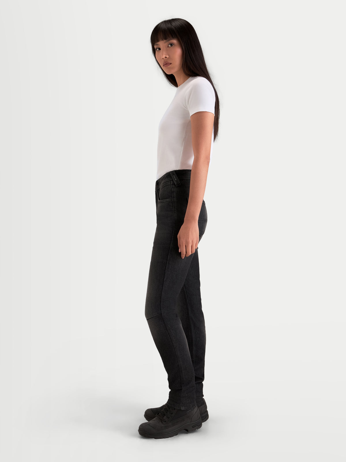 Alpinestars Stella Flex Ast 7 Denim calças, calças de moto urbanas para mulher em preto desbotado, vista de perfil lateral num modelo a usar ganga de proteção e botas a condizer