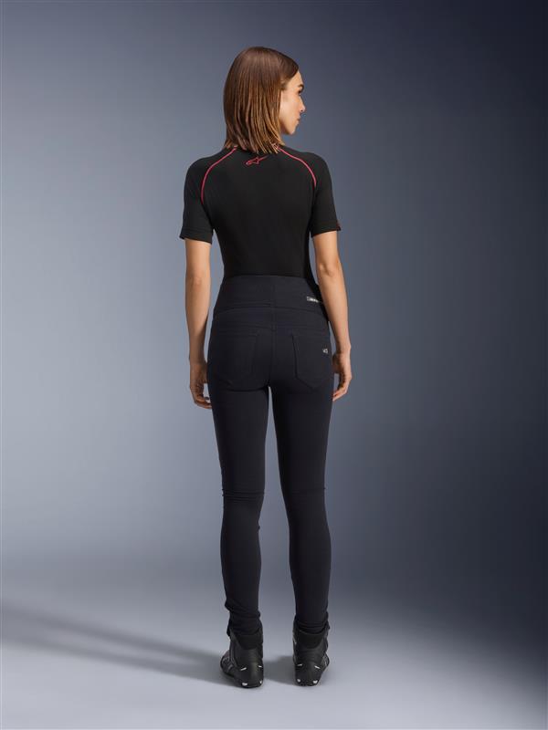 Alpinestars Stella Flex-Ast Leggings, leggings de motociclismo para mulher, pretas, vista traseira exibindo o corte justo de cintura alta, usadas com top preto de manga curta e botas de condução pretas, equipamento de condução urbana