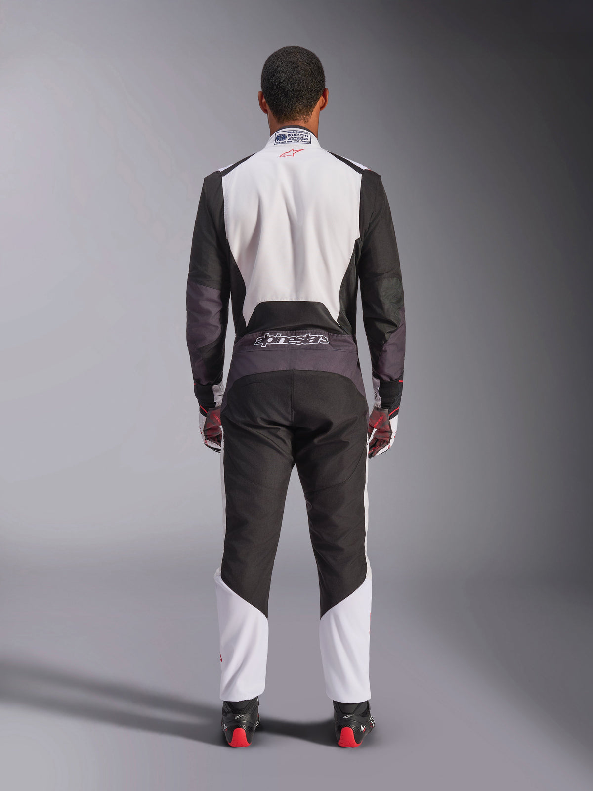 Alpinestars KMX-5 V3 Suit, Karting Suit, White Black and Bright Red, back view, one-piece racing suit with breathable mesh panels and Alpinestars logo on the waist, worn with matching racing gloves and boots