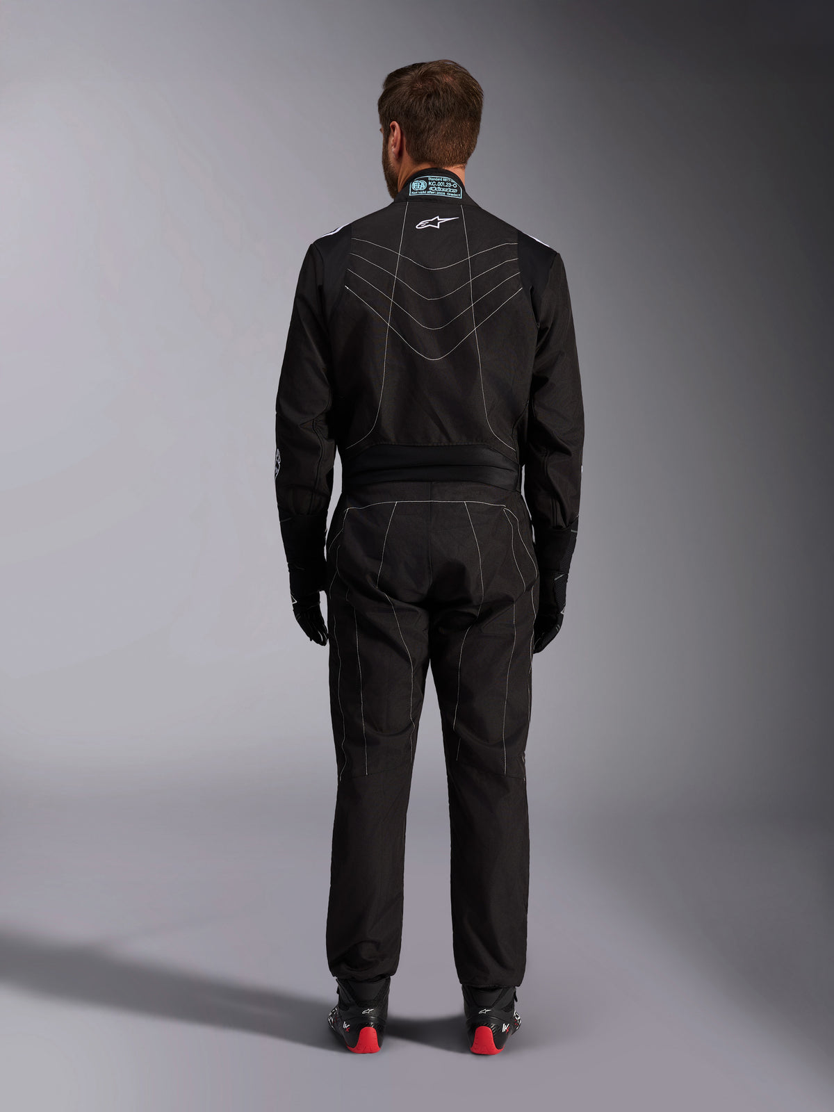 Alpinestars KMX-9 V3 Suit, Karting Suit, Black and White, rear view showing white contrast stitching, FIA homologation label on the collar, and stretch panels for mobility