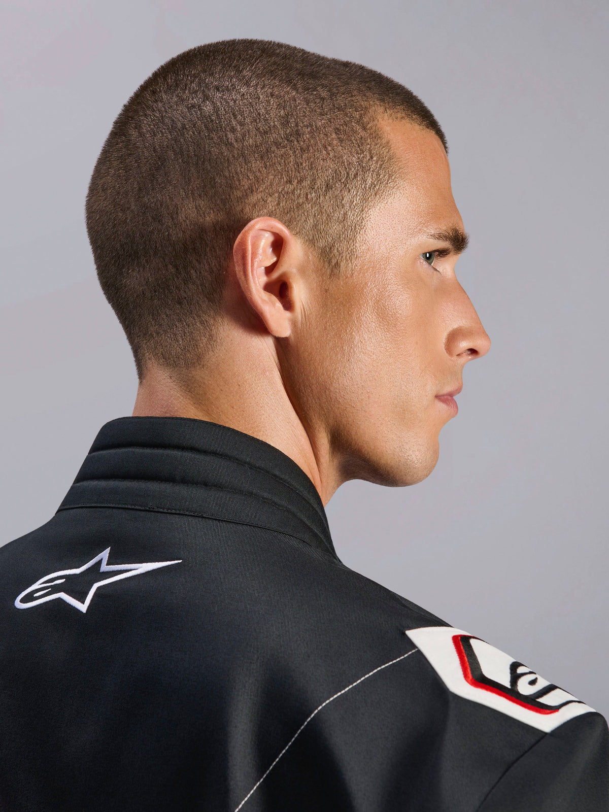 Fato Alpinestars Kart Indoor V2, Preto, vista aproximada da gola ergonómica e do design de ombro derivado da Fórmula 1, com o logótipo Alpinestars em branco e detalhes inspirados na competição em tecido de sarja durável
