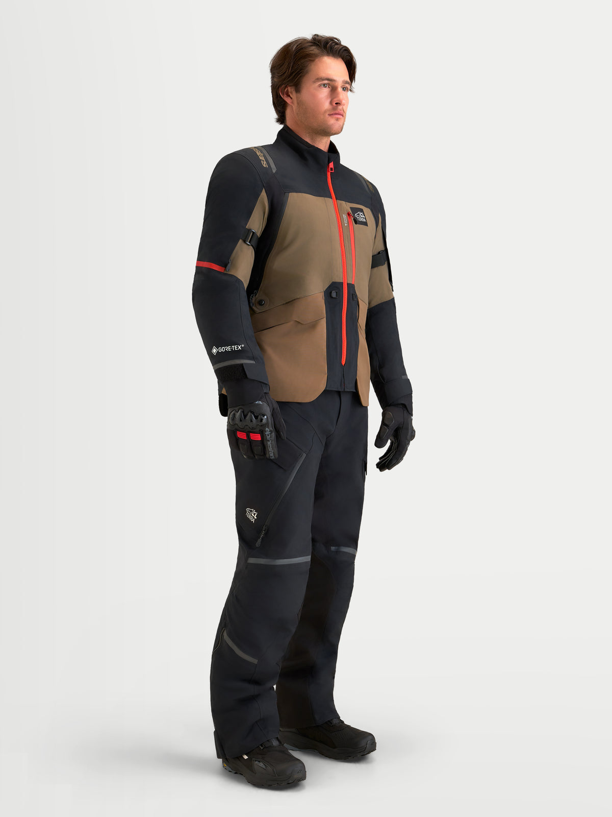 Alpinestars St-7 V2 2L Gore-Tex Gear Set, blusão e calças de moto para touring em preto e castanho, vestido num modelo a mostrar construção têxtil impermeável e detalhes de fecho vermelhos de alta visibilidade