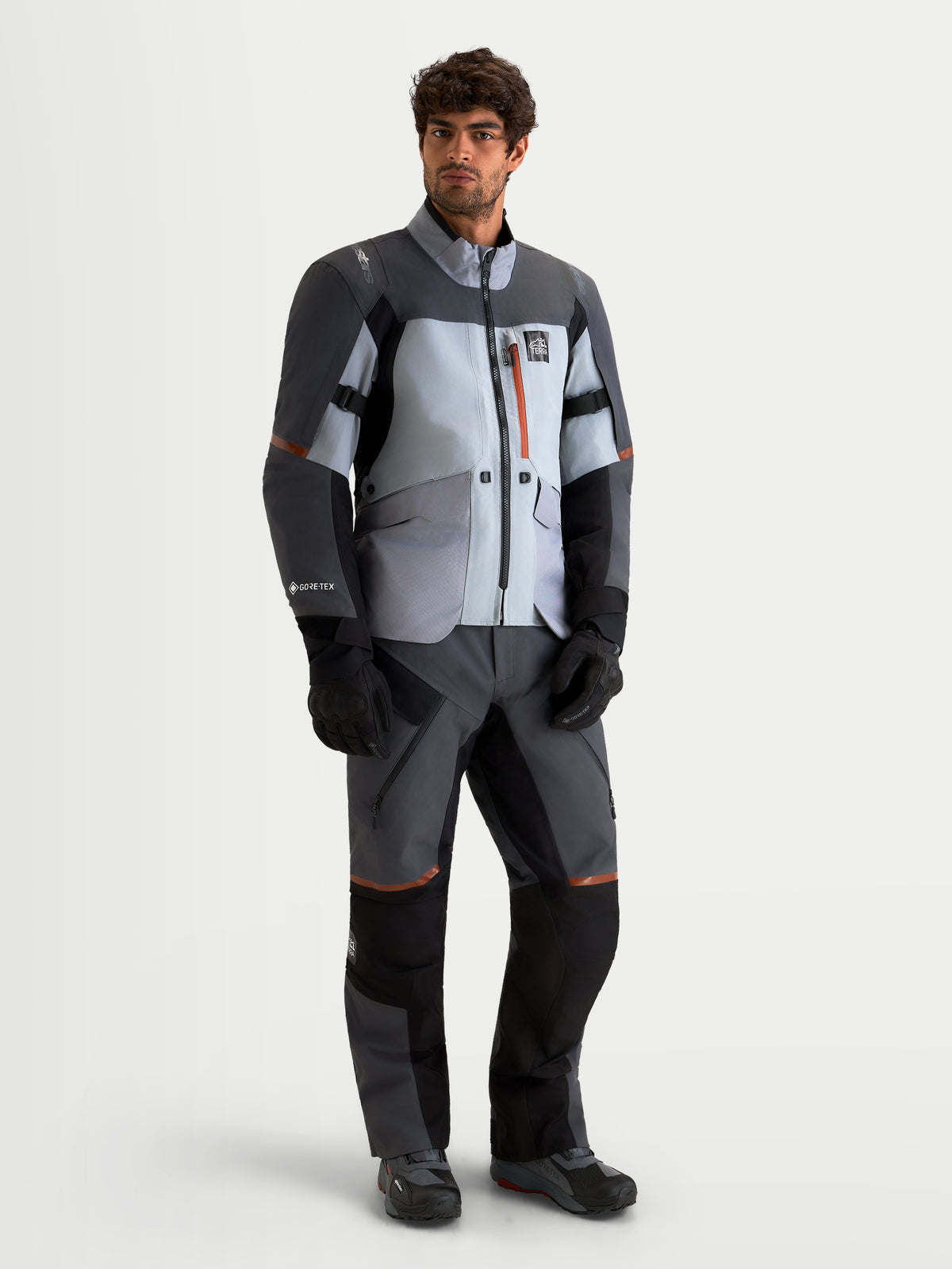Alpinestars St-7 V2 2L Gore-Tex Gear Set, adventure touring motorcycle jacket and pants in gray, black, and orange accents, worn by a model showcasing waterproof textile construction.
