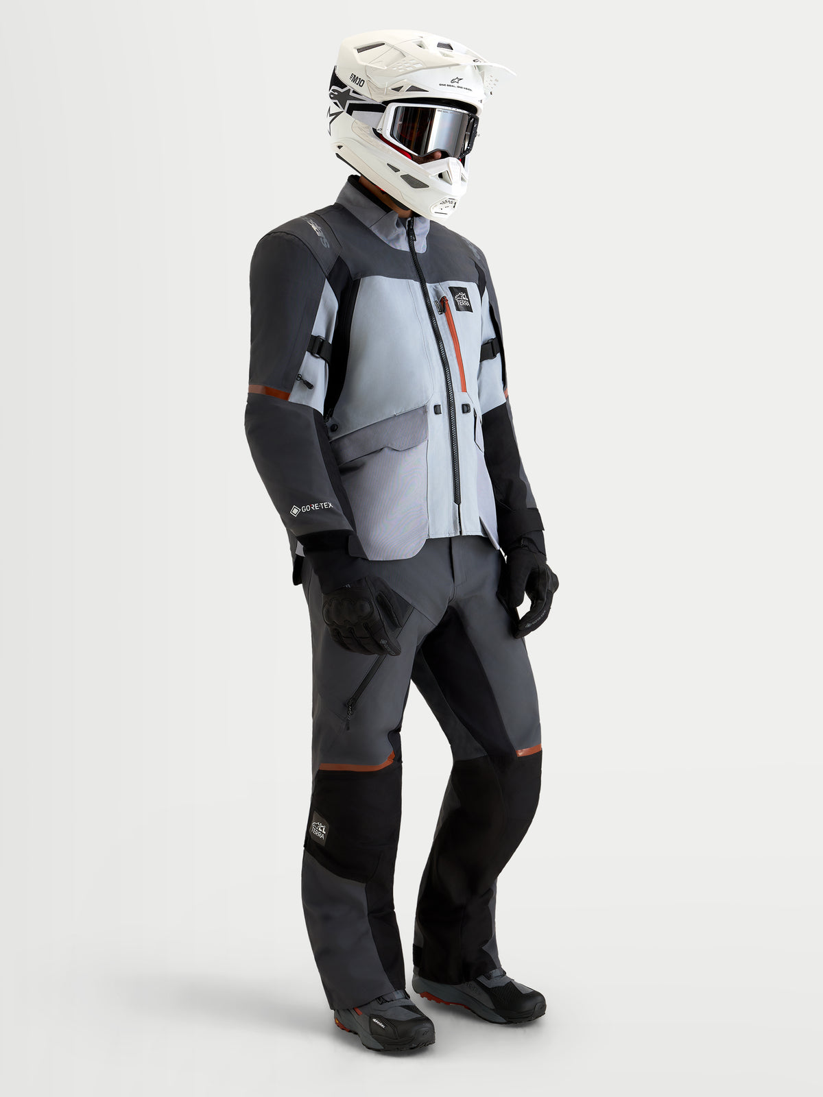 Alpinestars St-7 V2 2L Gore-Tex® Gear Set, adventure touring motorcycle jacket and pants in mid gray, deep gray, and black, worn by a model with matching helmet and gloves, waterproof textile construction.