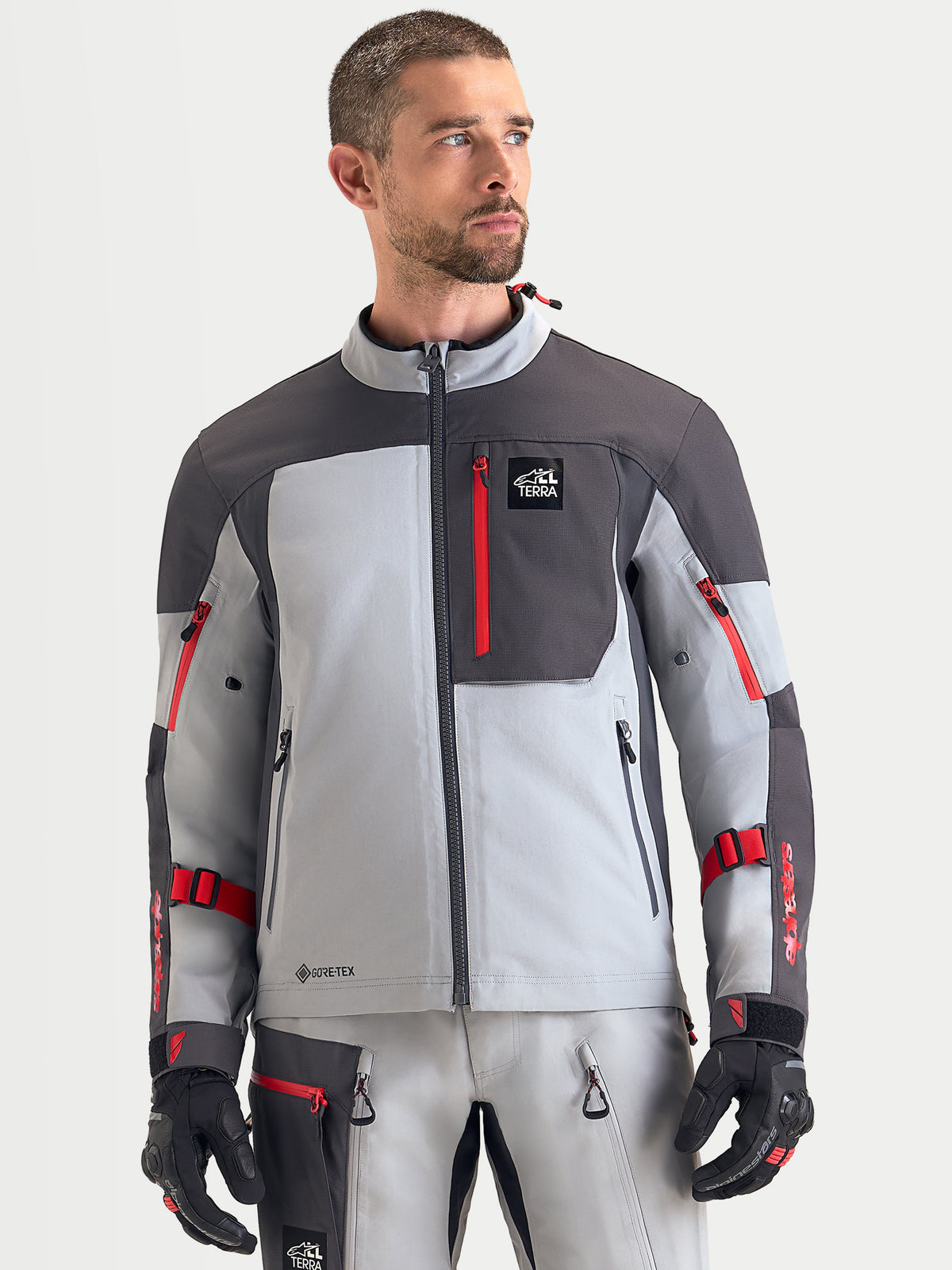 Alpinestars Arenis Gore-Tex casaco de moto para homem, cinzento-médio, cinzento-escuro e preto, vista frontal num modelo a mostrar a construção têxtil impermeável e o bolso com fecho no peito