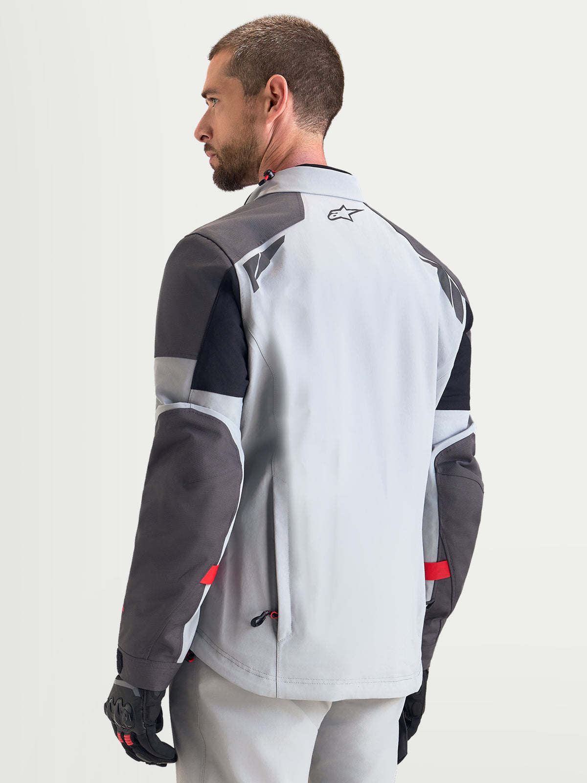 Alpinestars Arenis Gore-Tex, casaco de moto para aventura para homem, cinzento-claro, cinzento-escuro e preto, vista traseira num modelo a mostrar construção têxtil impermeável e pormenores refletores nos ombros