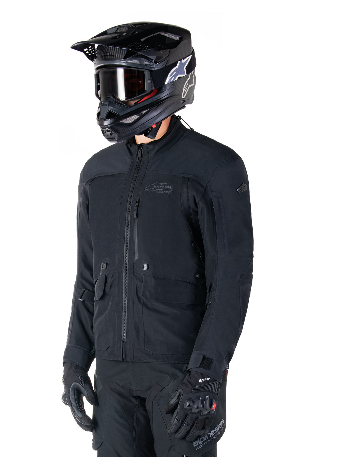 Casaco Alpinestars St-7 Prime GORE-TEX, casaco de motociclismo preto, usado por um motociclista com capacete preto e óculos, com grandes bolsos de carga no peito e uma camada exterior impermeável laminada, equipamento premium para turismo de aventura e deslocações diárias