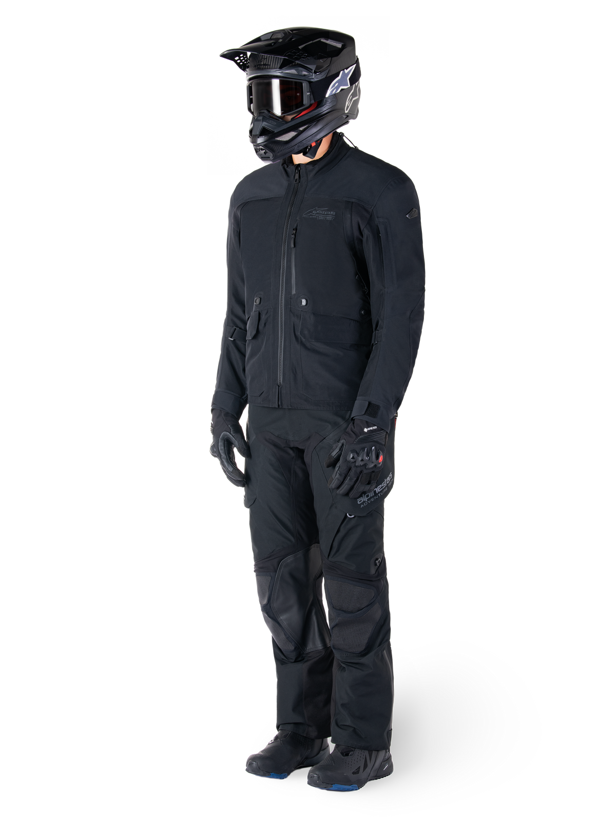Motociclista a usar o Casaco Alpinestars St-7 Prime GORE-TEX em preto, equipamento de aventura e touring coordenado com calças pretas a condizer, capacete preto com óculos e luvas, com um design aerodinâmico e funcional para desempenho em todas as condições climatéricas.