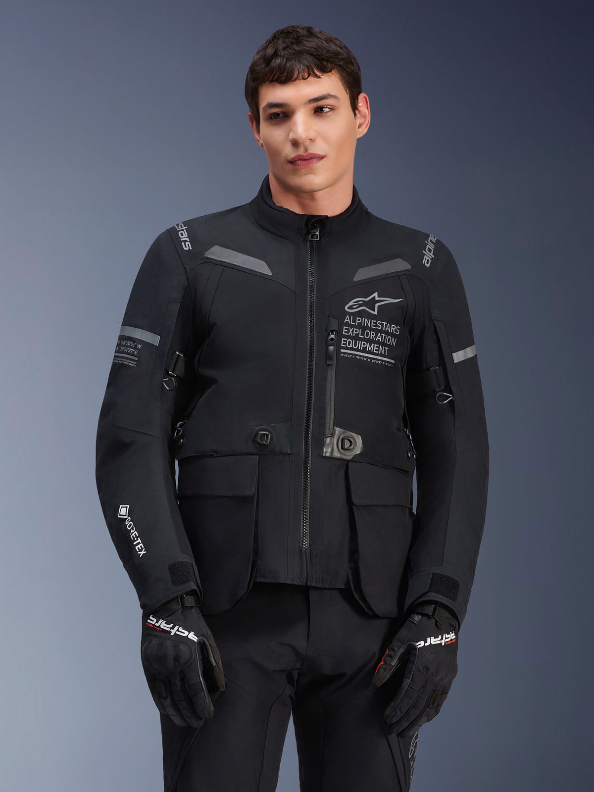 Casaco Alpinestars ST-7 2L GORE-TEX, casaco de motociclismo para turismo, preto e cinzento escuro, com logótipo Alpinestars Exploration Equipment no peito, grandes bolsos cargo impermeáveis, logótipo GORE-TEX na manga e detalhes refletores