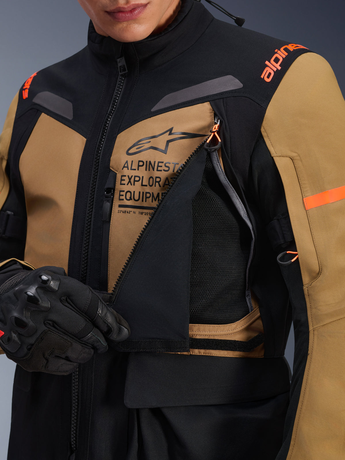 Casaco Alpinestars ST-7 2L GORE-TEX, casaco de motociclismo Adventure Touring, castanho Gobi e preto, grande plano do painel de ventilação no peito aberto revelando malha respirável, marca Alpinestars Exploration Equipment e detalhes em laranja