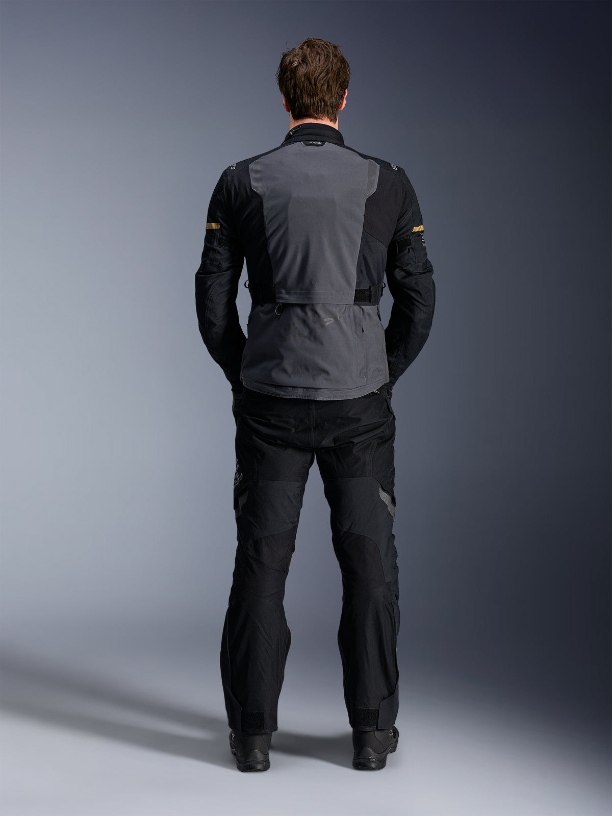Casaco Alpinestars ST-7 2L GORE-TEX, Deep Gray Black e Dark Khaki, vista traseira num modelo, casaco de touring de aventura para motociclismo com painel traseiro cinzento e mangas articuladas pretas, usado com calças pretas a condizer