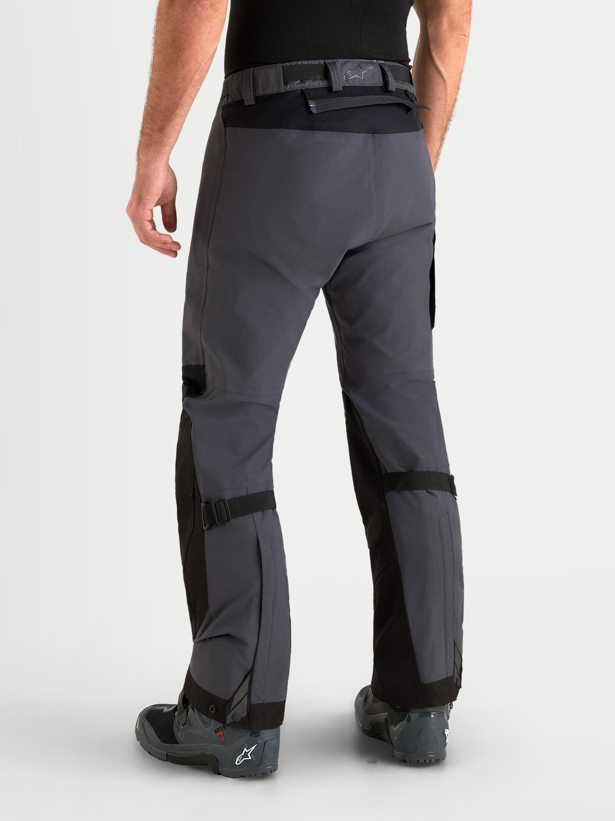 Alpinestars Arenis Gore-Tex calças de moto para homem, pretas e cinzentas-escuras, vista traseira num modelo a mostrar construção têxtil impermeável e fecho na cintura