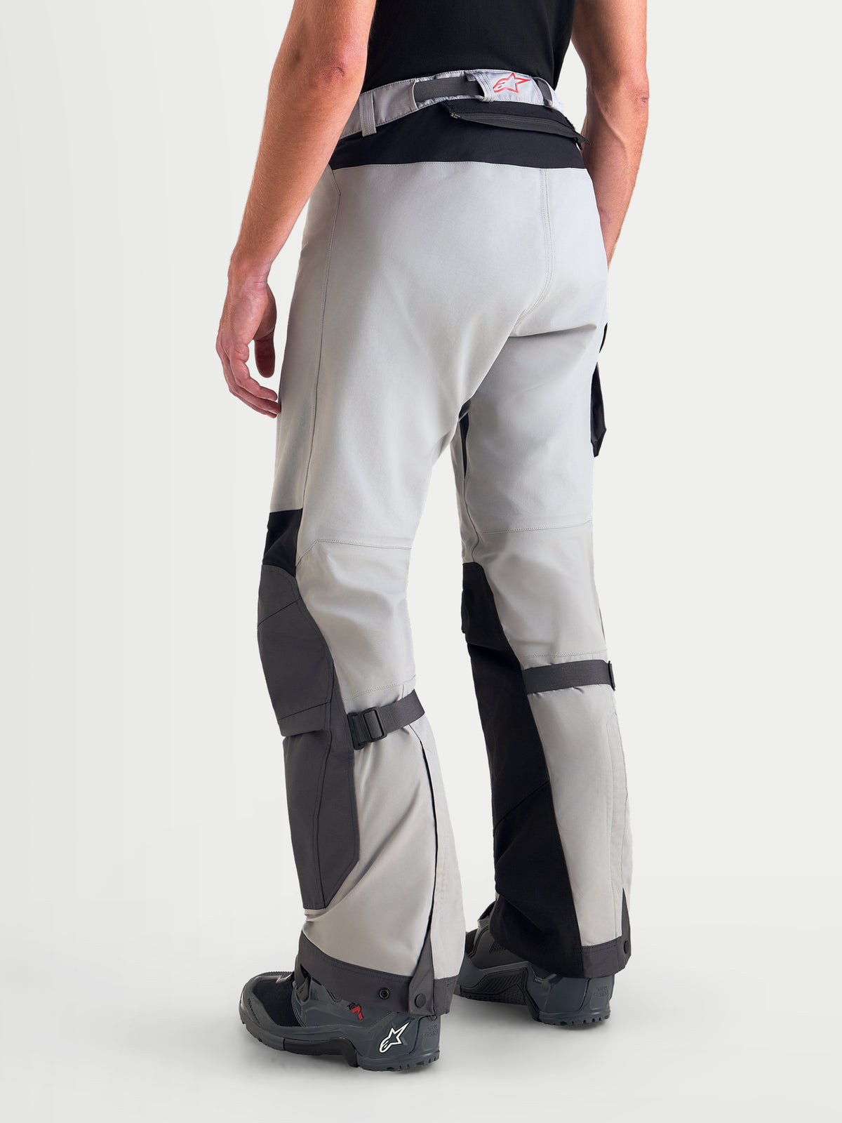 Alpinestars Arenis Gore-Tex calças, calças de moto adventure para homem em cinzento médio, cinzento escuro e preto, vista traseira de três quartos num modelo a mostrar construção em tecido impermeável e zonas reforçadas nos joelhos e assento
