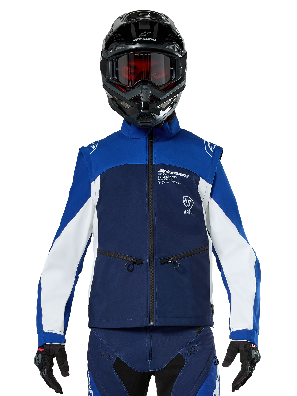 Piloto de motocross a usar o Casaco Alpinestars Lite-Dura Softshell em azul-marinho, azul brilhante e branco, vista frontal, combinado com capacete preto e óculos de lentes vermelhas, apresentando um design técnico à prova de vento com bolsos de fecho e detalhes brancos para condução de enduro todo-o-terreno