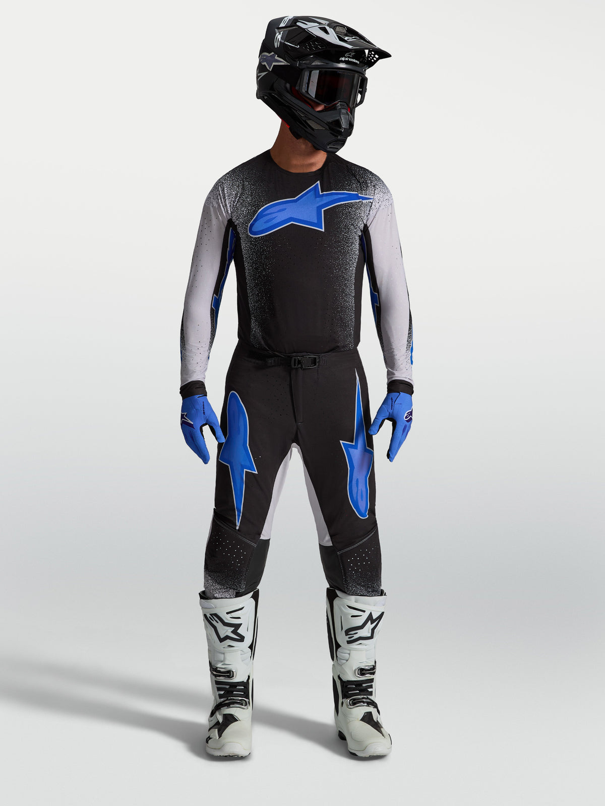 Alpinestars calças Supertech Hiten AFD, calças de motocross pretas e azuis, com camisola a condizer e botas de moto brancas.