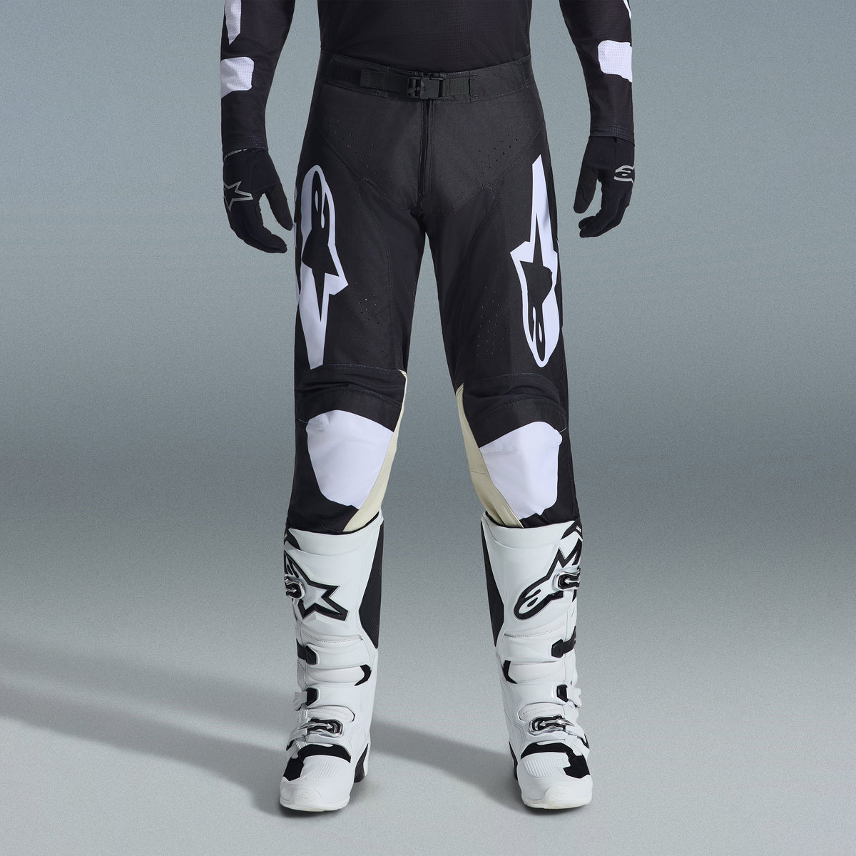 Alpinestars 2026 Racer Air Riway Gear Set, calças de motocross pretas e brancas com painéis interiores nos joelhos em bege, combinadas com botas de corrida brancas e luvas pretas, equipamento de corrida todo-o-terreno leve e ventilado