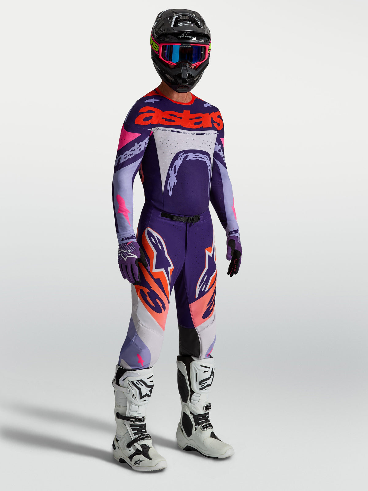 Alpinestars Calças Supertech Dyna, calças de motocross para homem, roxas e rosa fluo, com botas de corrida brancas.