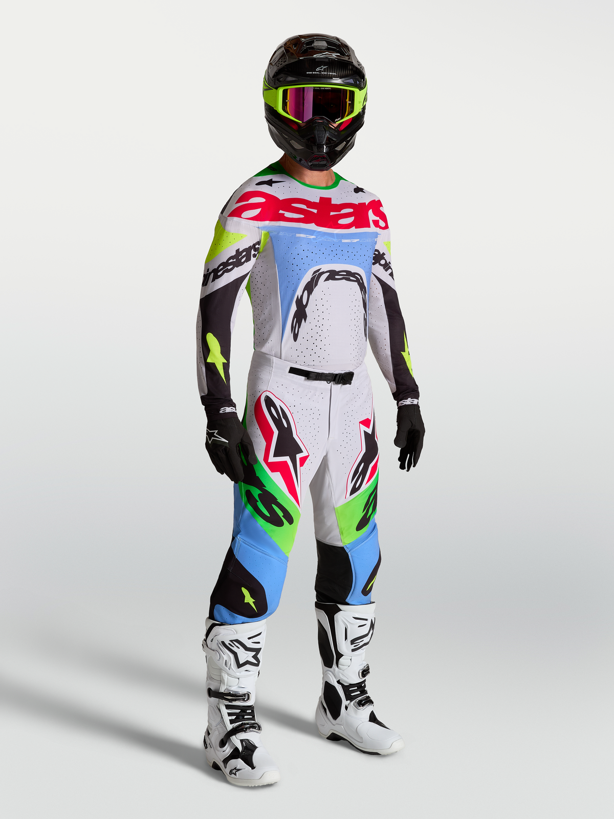 Alpinestars Supertech Dyna, calças de motocross para homem, lilás claro e verde fluorescente, num equipamento de corrida completo.