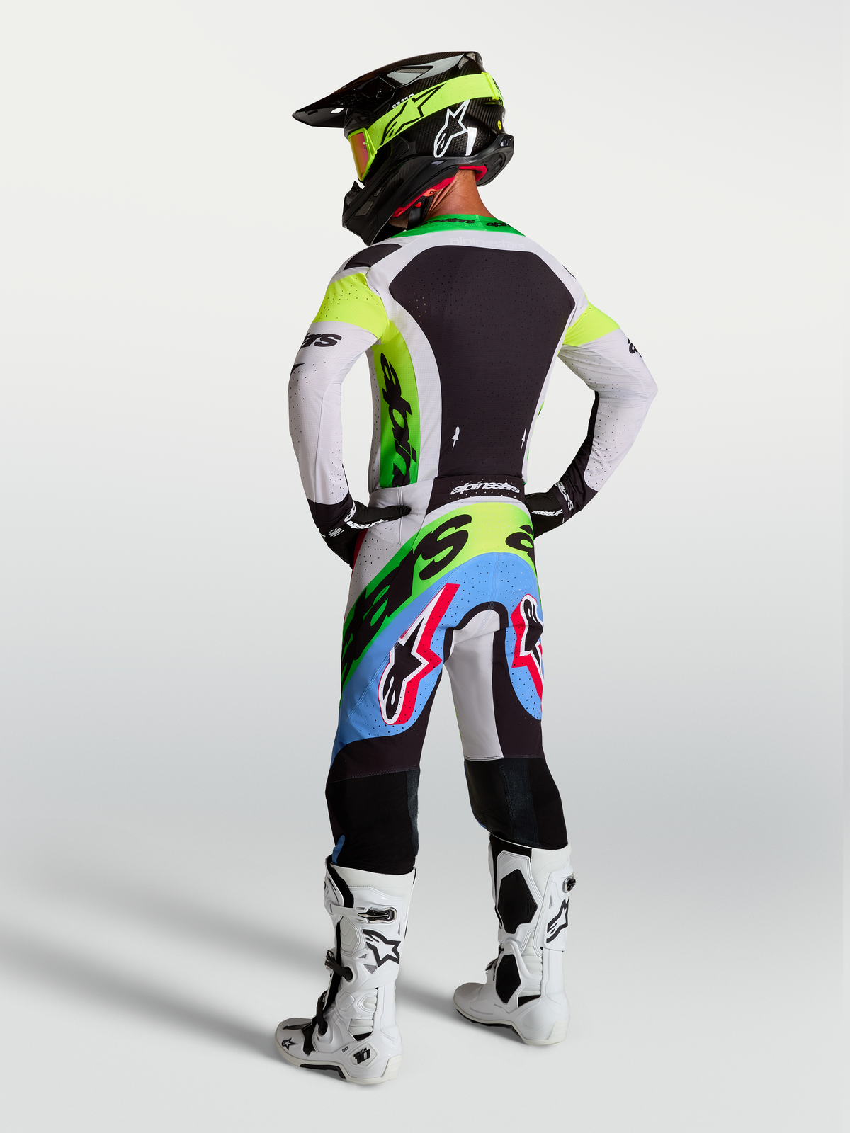 Alpinestars Supertech Dyna, equipamento de motocross verde fluo, preto e lilás claro, com calças e camisola, vista traseira.