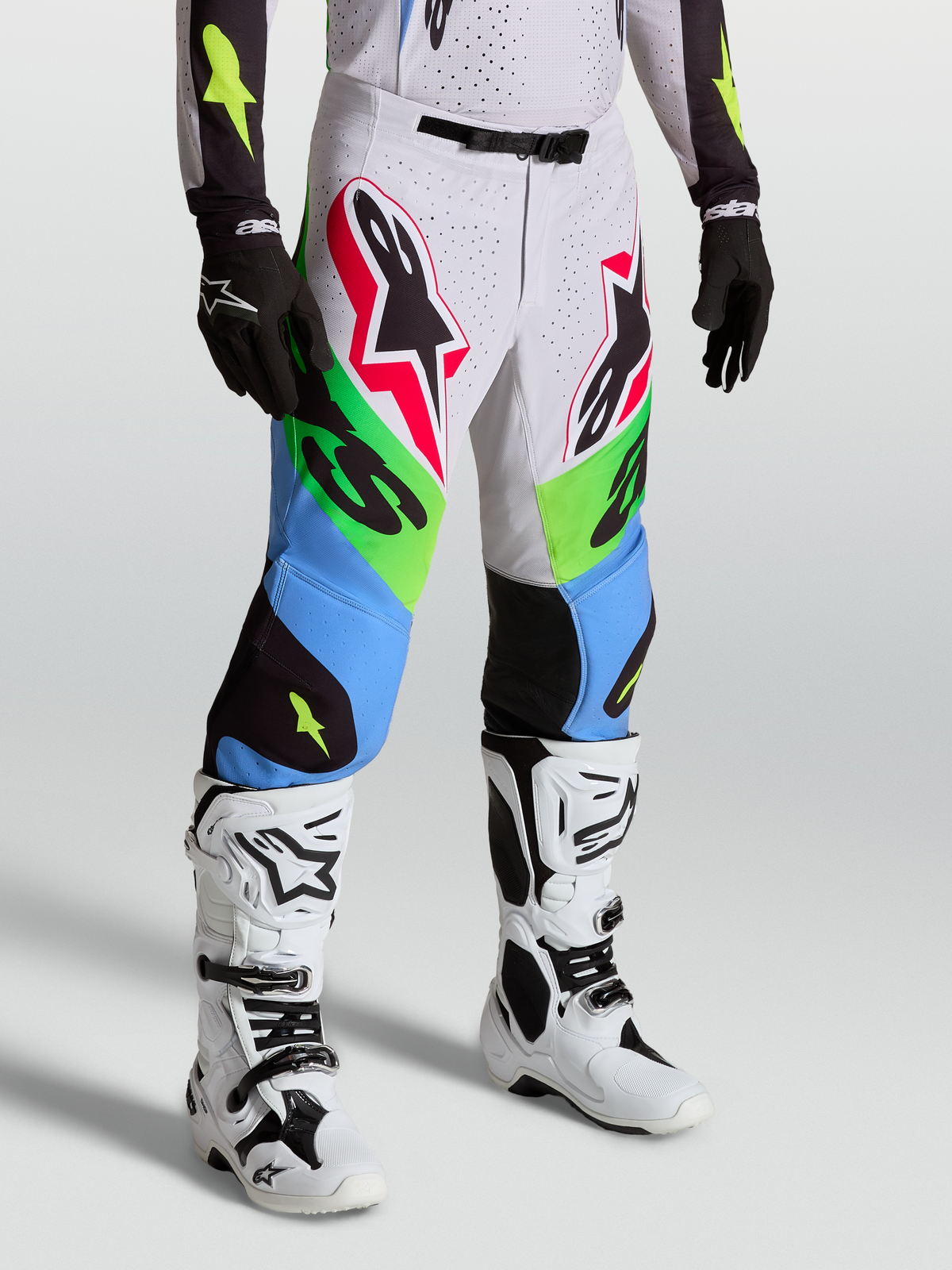 Alpinestars Supertech Dyna, calças de motocross profissionais, verdes e azuis, modelo com botas brancas e luvas pretas