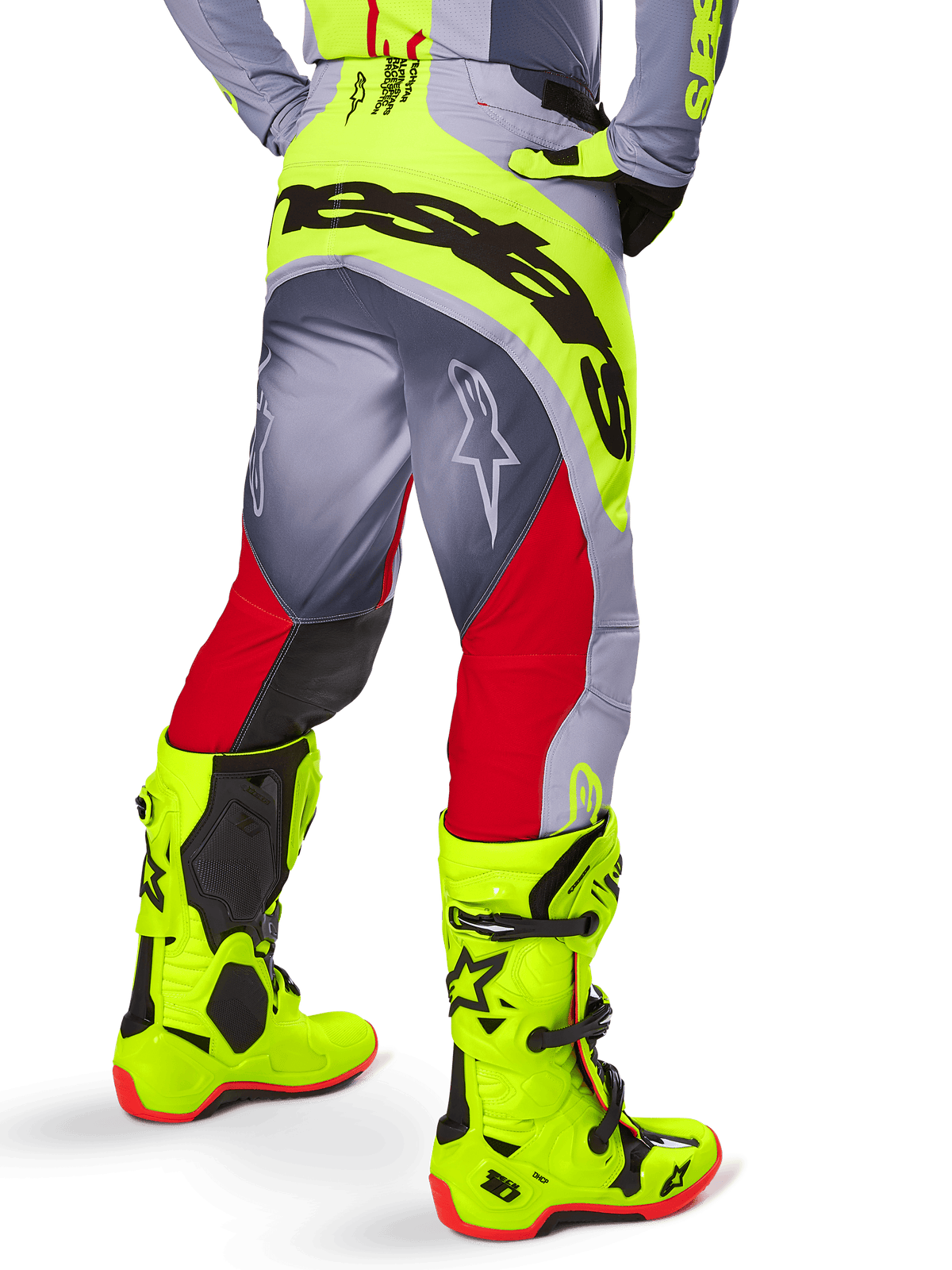Alpinestars 2025 Techstar Melt Pants, calças de motocross, vermelho brilhante e cinzento com detalhes em amarelo néon, vista traseira realçando o logótipo preto de grandes dimensões no assento, usadas com botas amarelo vibrante a condizer e camisola cinzenta, corte atlético de corrida para competição todo-o-terreno.