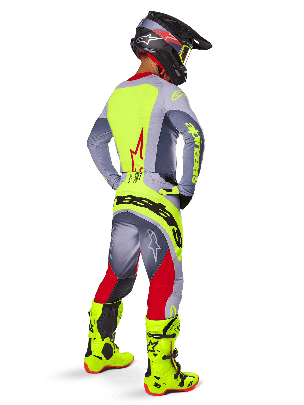 Piloto de motocross a usar o conjunto de equipamento Alpinestars 2025 Techstar Melt, visto de costas. Camisola cinzenta com painel traseiro amarelo néon e logótipo de estrela vermelho, calças cinzentas e vermelhas com a marca 'Alpinestars' em amarelo néon no assento, botas de motocross amarelo néon vibrante e capacete a condizer.