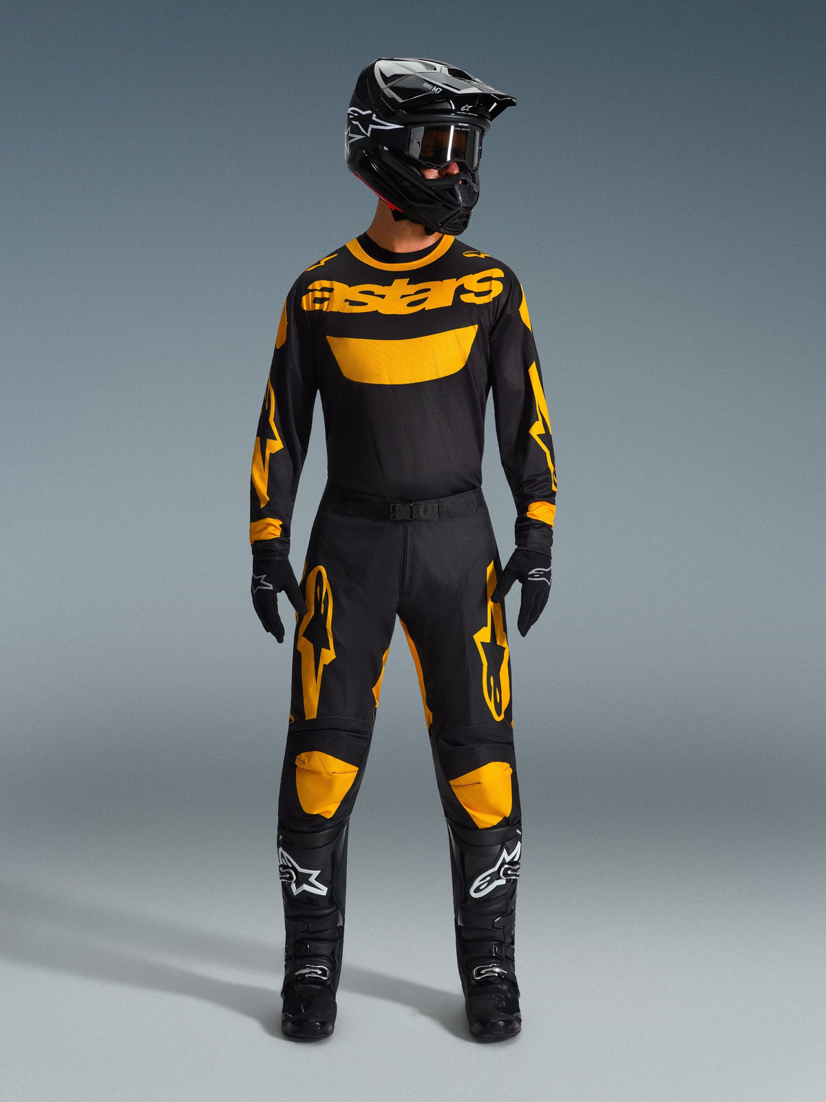 Alpinestars 2026 Racer Riway Pants, calças de motocross, amarelas e pretas, usadas como um conjunto de corrida completo com camisola de manga comprida a condizer, capacete preto, óculos pretos e botas pretas com logótipos de estrela brancos, equipamento profissional de condução off-road