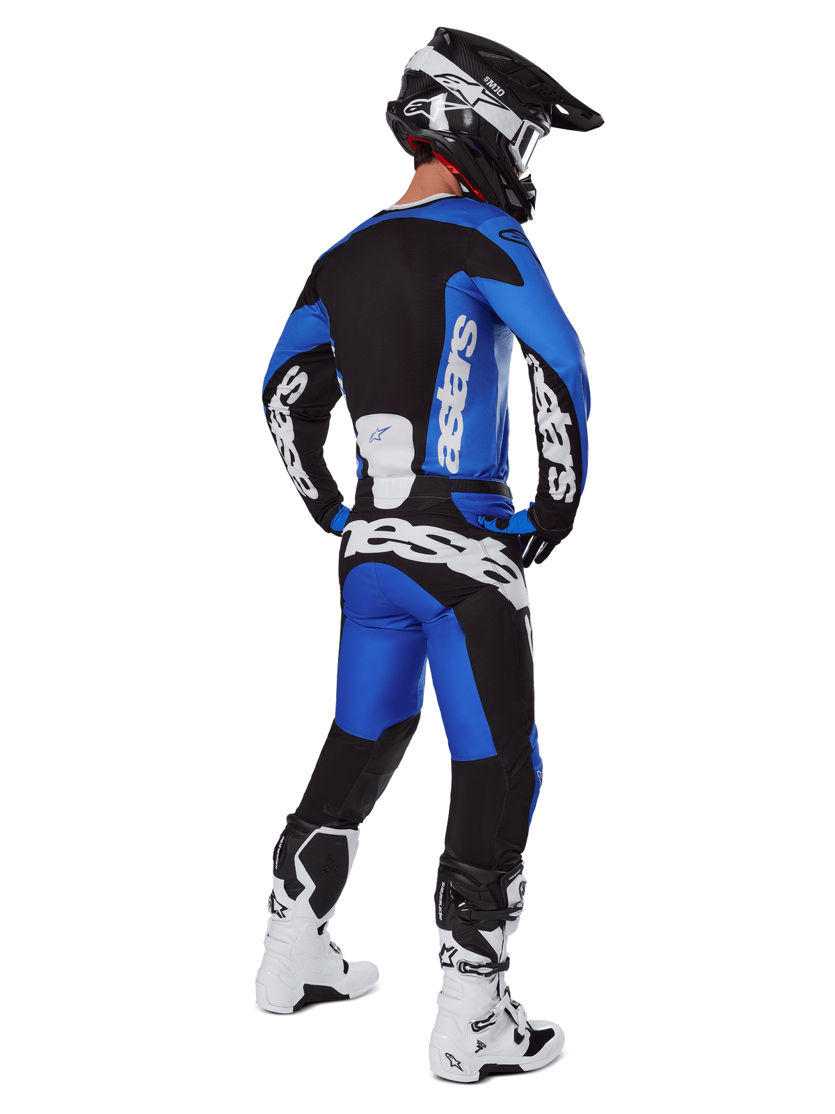 Piloto de motocross visto de costas a usar calças Alpinestars 2025 Racer Veil em azul e preto, camisola de manga comprida a condizer com logótipos brancos, botas Tech 7 brancas e pretas e um capacete SM10 preto, conjunto completo de equipamento de corrida off-road