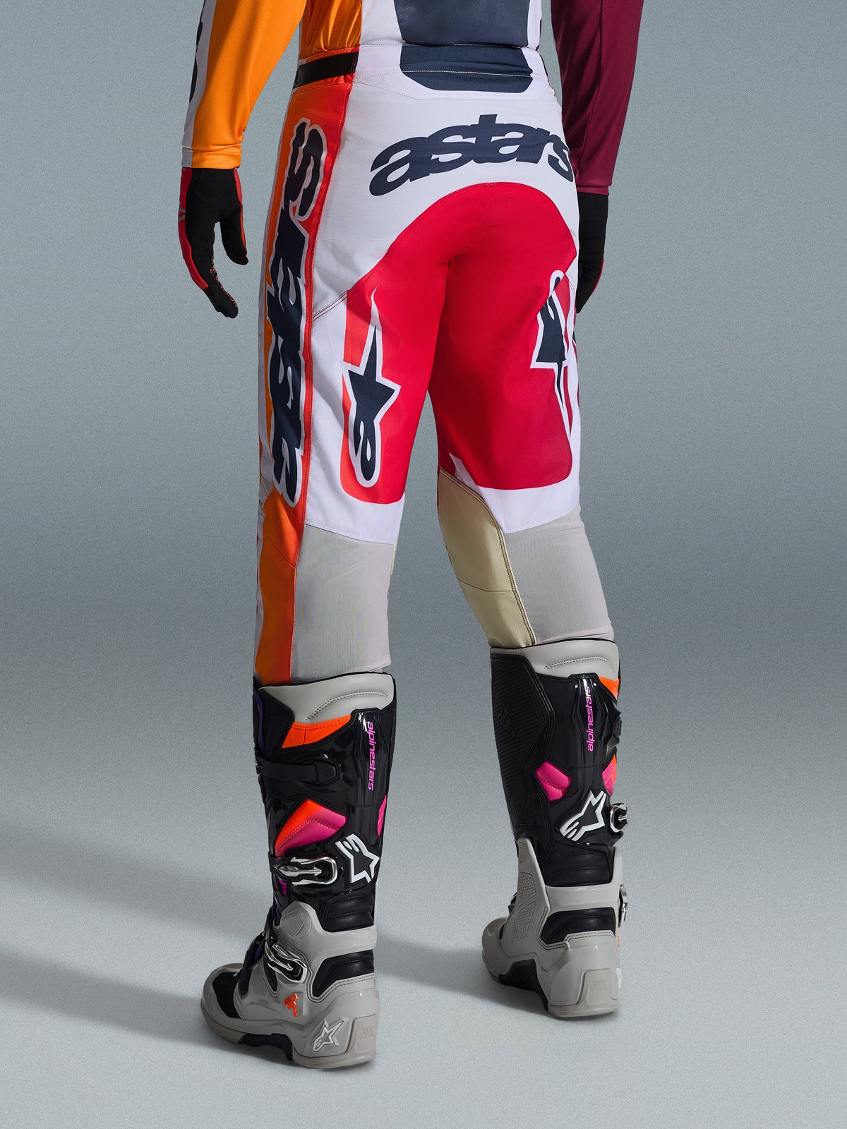 Calças Alpinestars 2026 Racer Portl, calças de motocross, vermelhas, cinzento claro e cinzento escuro, vista traseira com detalhes de marca e logótipo arrojados, combinadas com botas e luvas de motocross coordenadas, equipamento de performance para corridas off-road