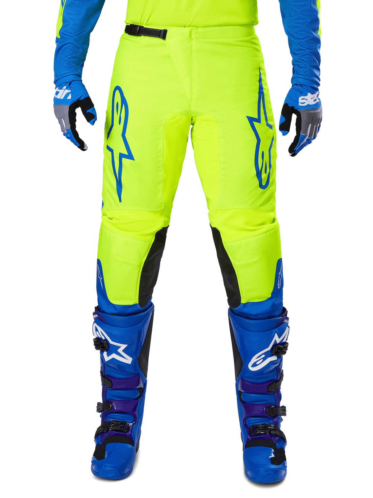 Alpinestars 2025 Fluid Haul Pants, calças de motocross, amarelo brilhante e azul, usadas com luvas e botas a condizer, com painéis pretos no interior dos joelhos, logótipos azuis marcantes nas coxas e um design ergonómico desportivo.