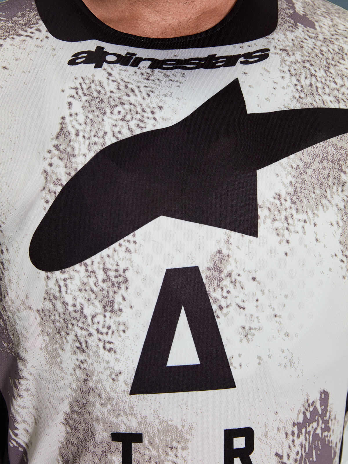 Camisola Alpinestars 2026 Racer Lahnd, detalhe da zona do peito, padrão Sand Camo com grande logótipo de estrela preto e inscrição Alpinestars, polifabric de performance respirável para condução off-road