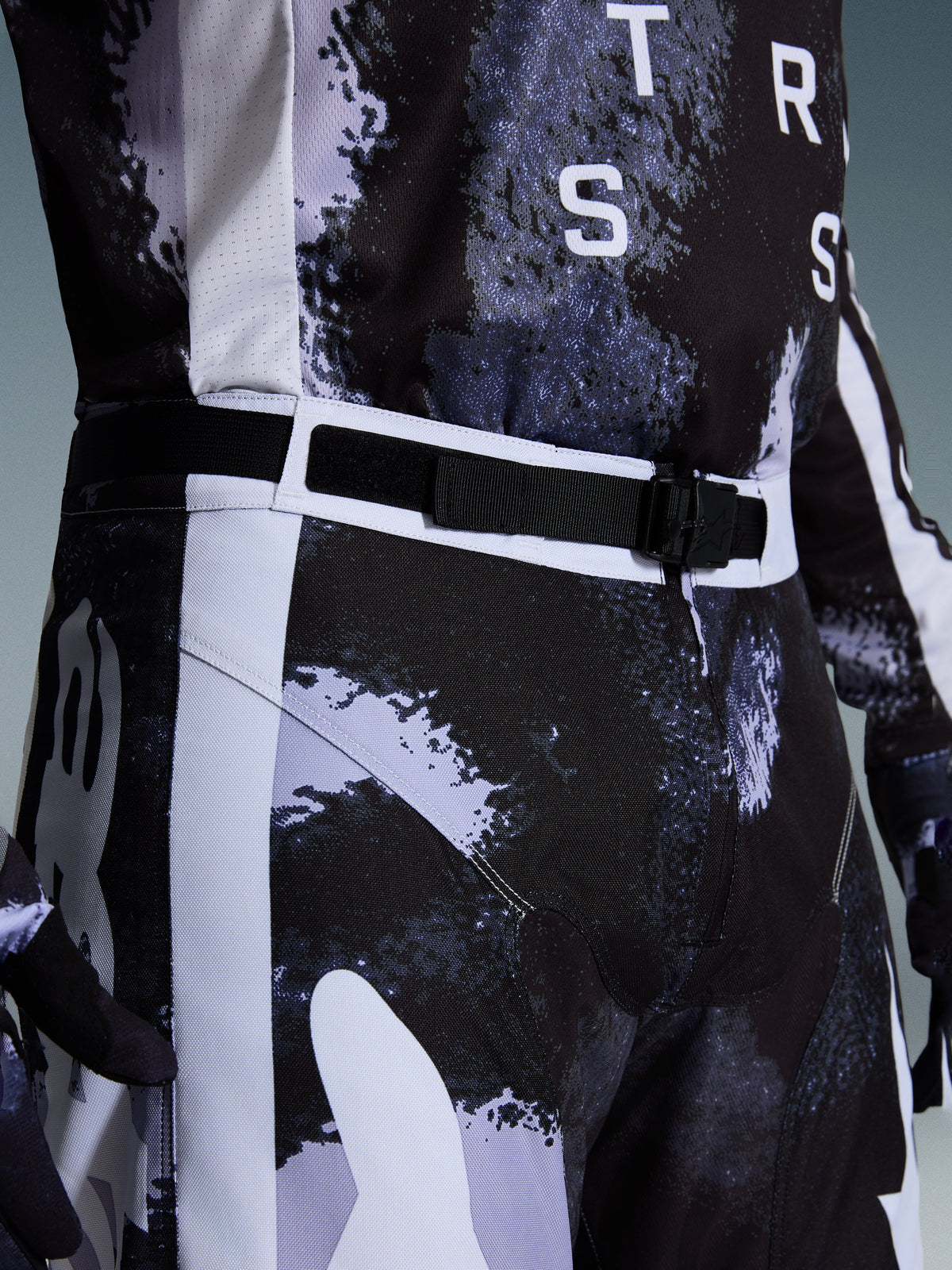 Calças Alpinestars 2026 Racer Lahnd, calças de motocross em Iron Camo, vista aproximada da cintura ajustável e da fivela magnética SX2, com padrão de camuflagem cinzento e preto e construção durável em polifabric 600D.