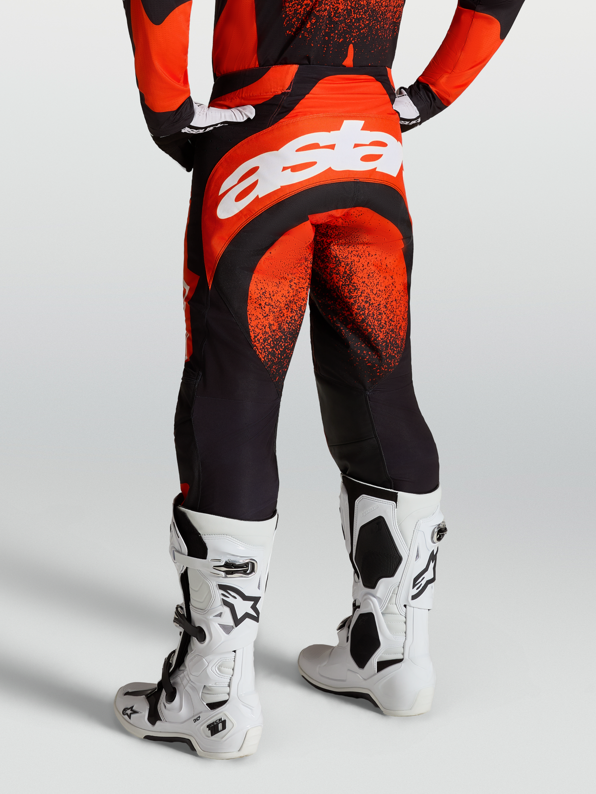 Alpinestars Calças Techstar Swan, calças de motocross para homem, vermelho cardinal e preto, logótipo Astar branco na traseira, exibidas com botas Tech 10 brancas.