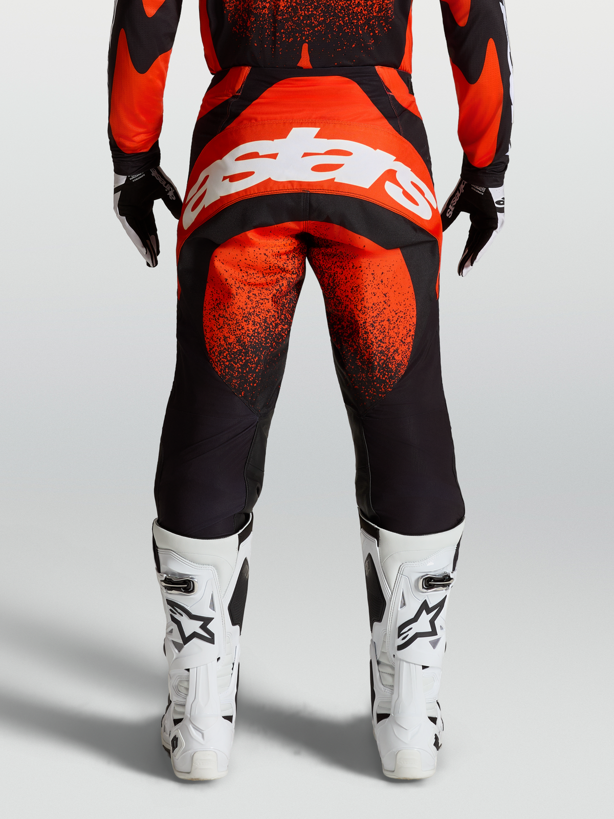 Alpinestars Calças Techstar Swan, calças de motocross para homem, vermelhas e pretas, vista traseira com logótipo branco e botas de corrida